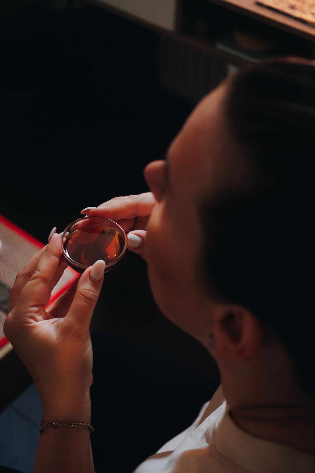Woman sipping tea from a small glass cup during a traditional Chinese tea tasting ceremony.