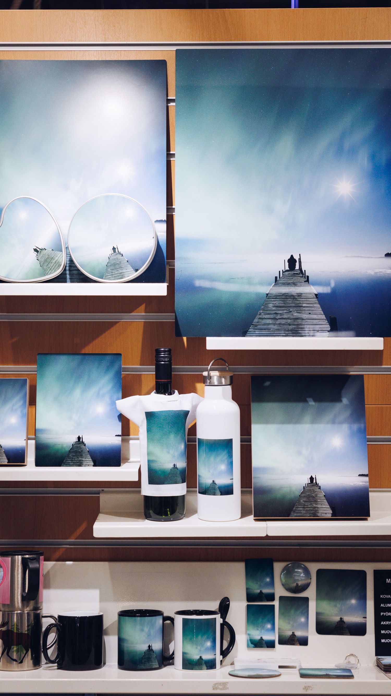 A display shelf featuring mugs, water bottles, and art prints with dreamy teal ocean and starry night sky designs.