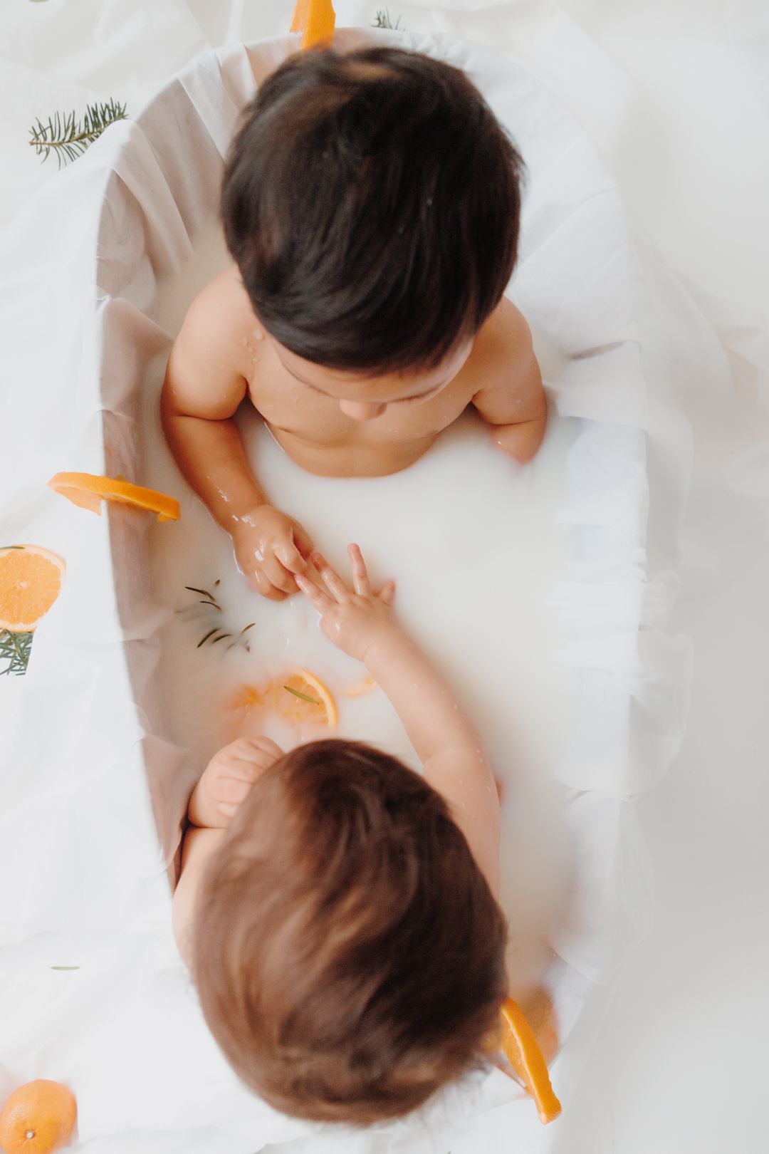 Infant dressed in white crawls on white background with orange accents in sequence of four connected photos.