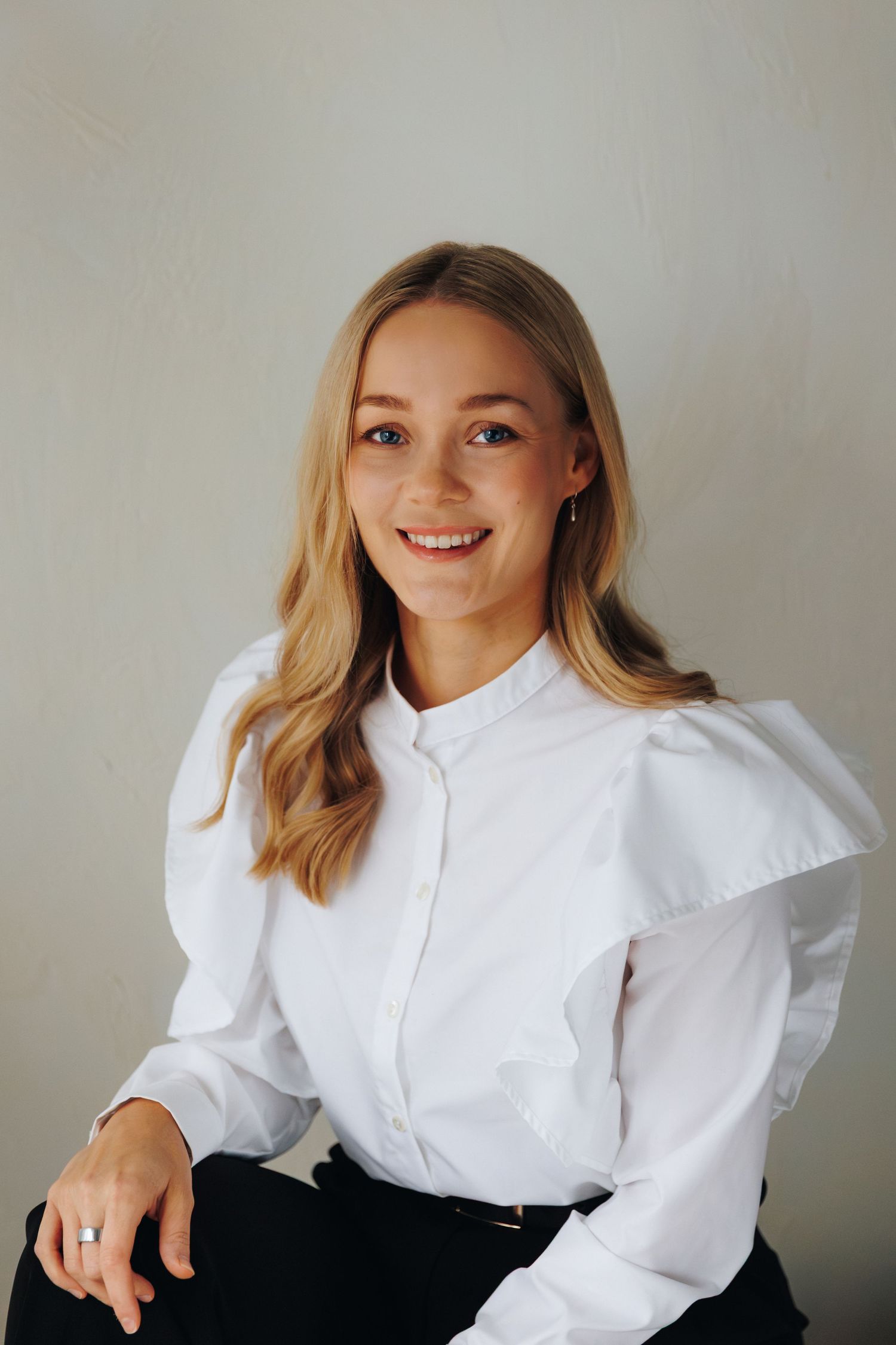 Professional portrait of someone wearing a crisp white button-up shirt with puff sleeves against a neutral background.