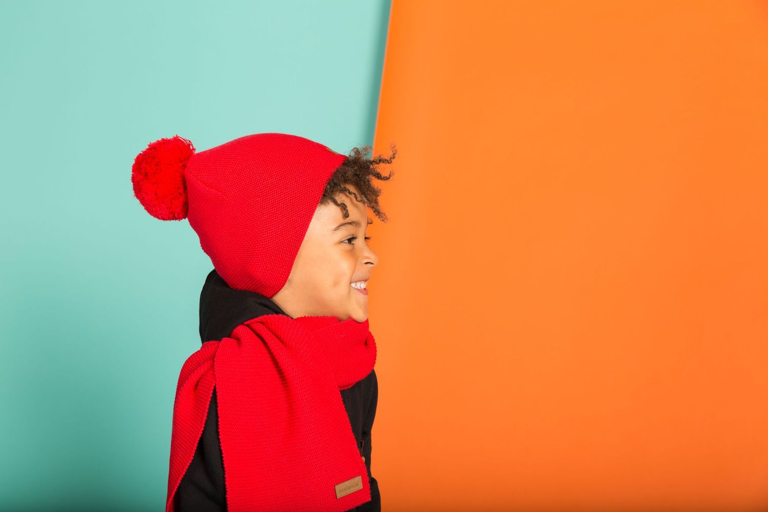 A person in a bright red hoodie is posed in different positions against contrasting orange and mint green backgrounds.