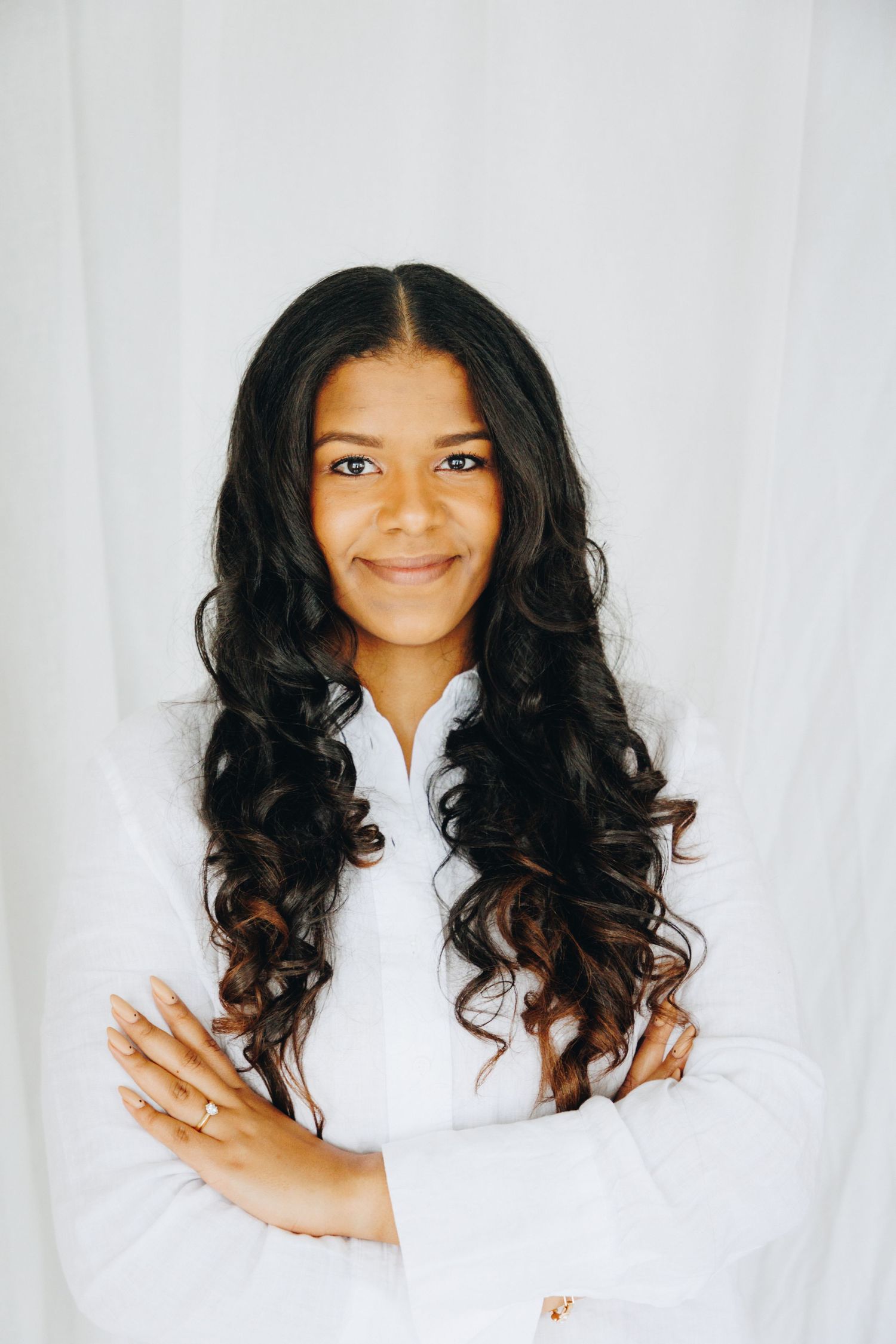Professional portrait series showing a person with long dark curly hair wearing a white top against a light background.