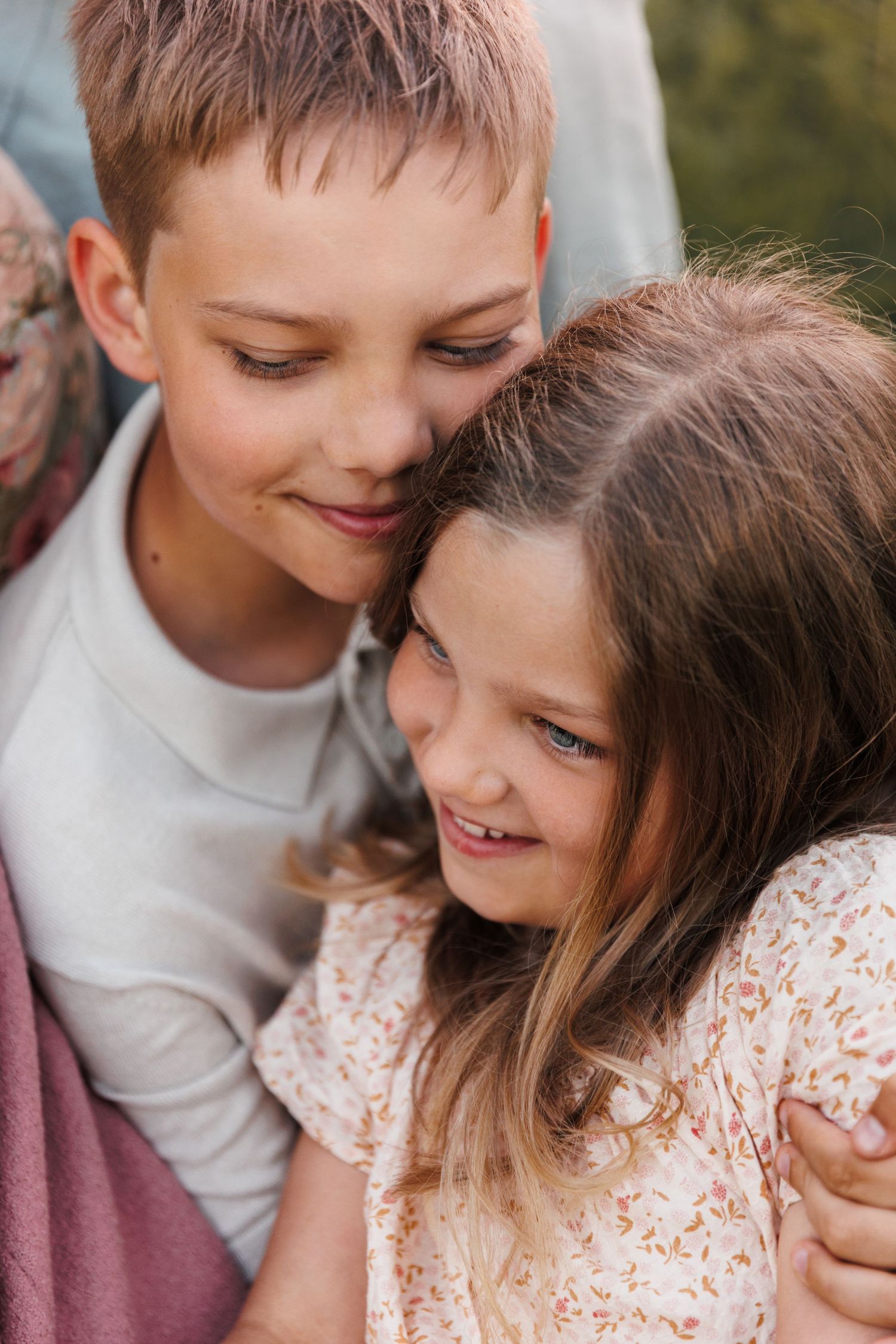 A boy and girl sharing a sweet moment outdoors, smiling together in a warm embrace.