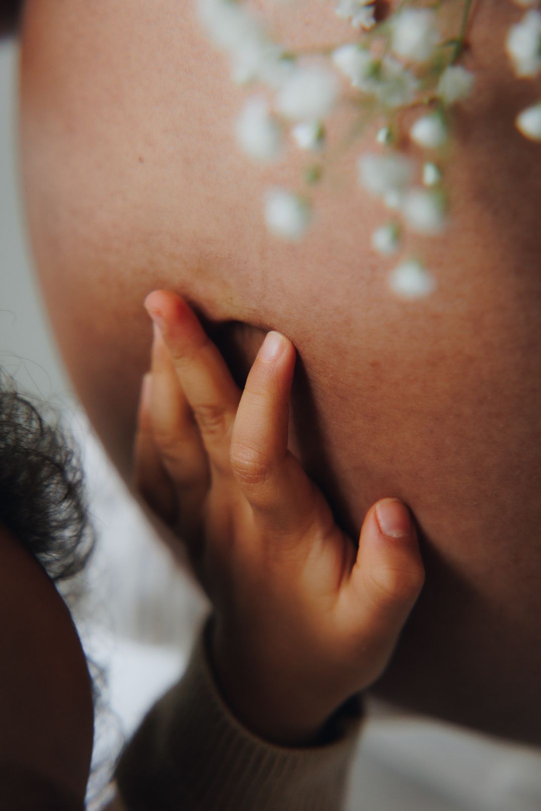 Close-up shot of a small child's hand reaching upward in soft lighting against a blurred background.