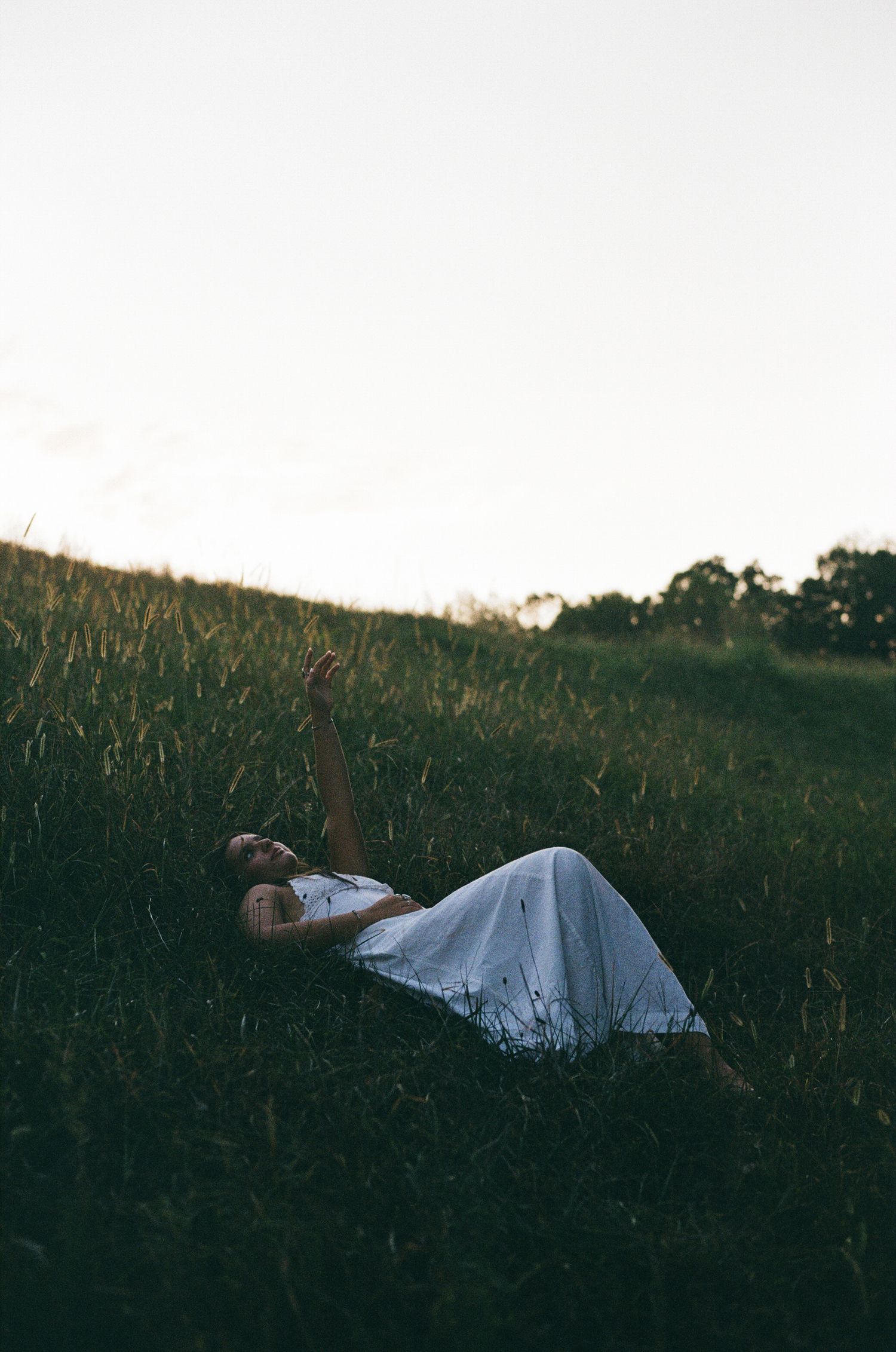 Photo of girl laying in grass with her hand in the air