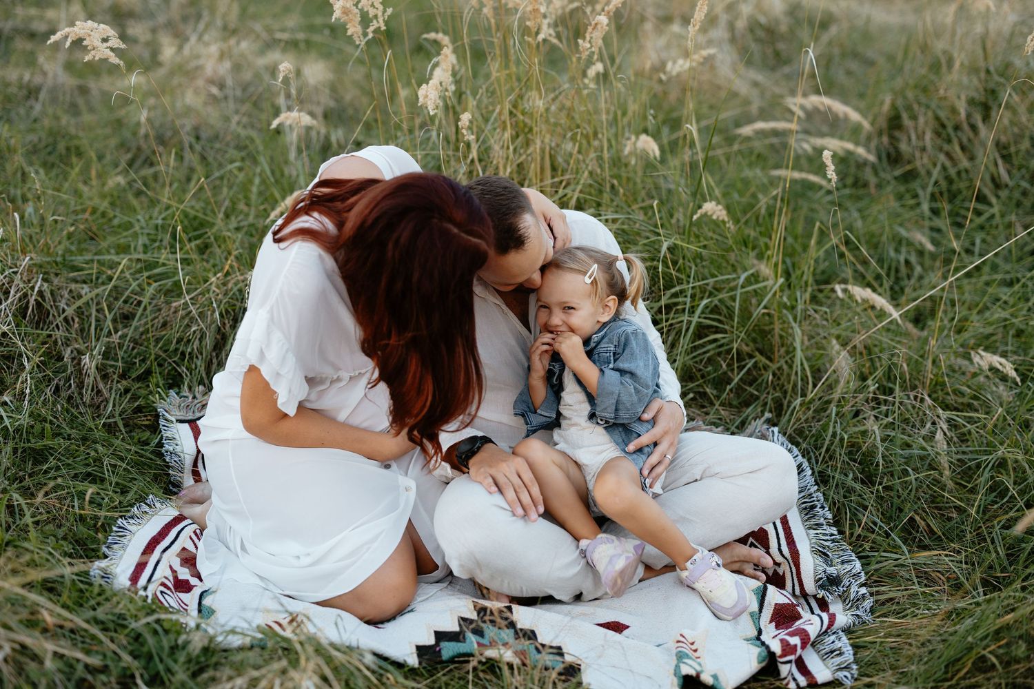 An intimate family moment shared on a blanket in a summer field.