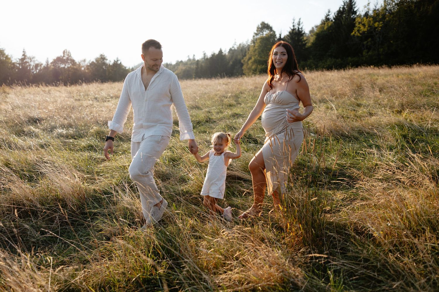 Family enjoying playful moments together in a sun-drenched meadow.