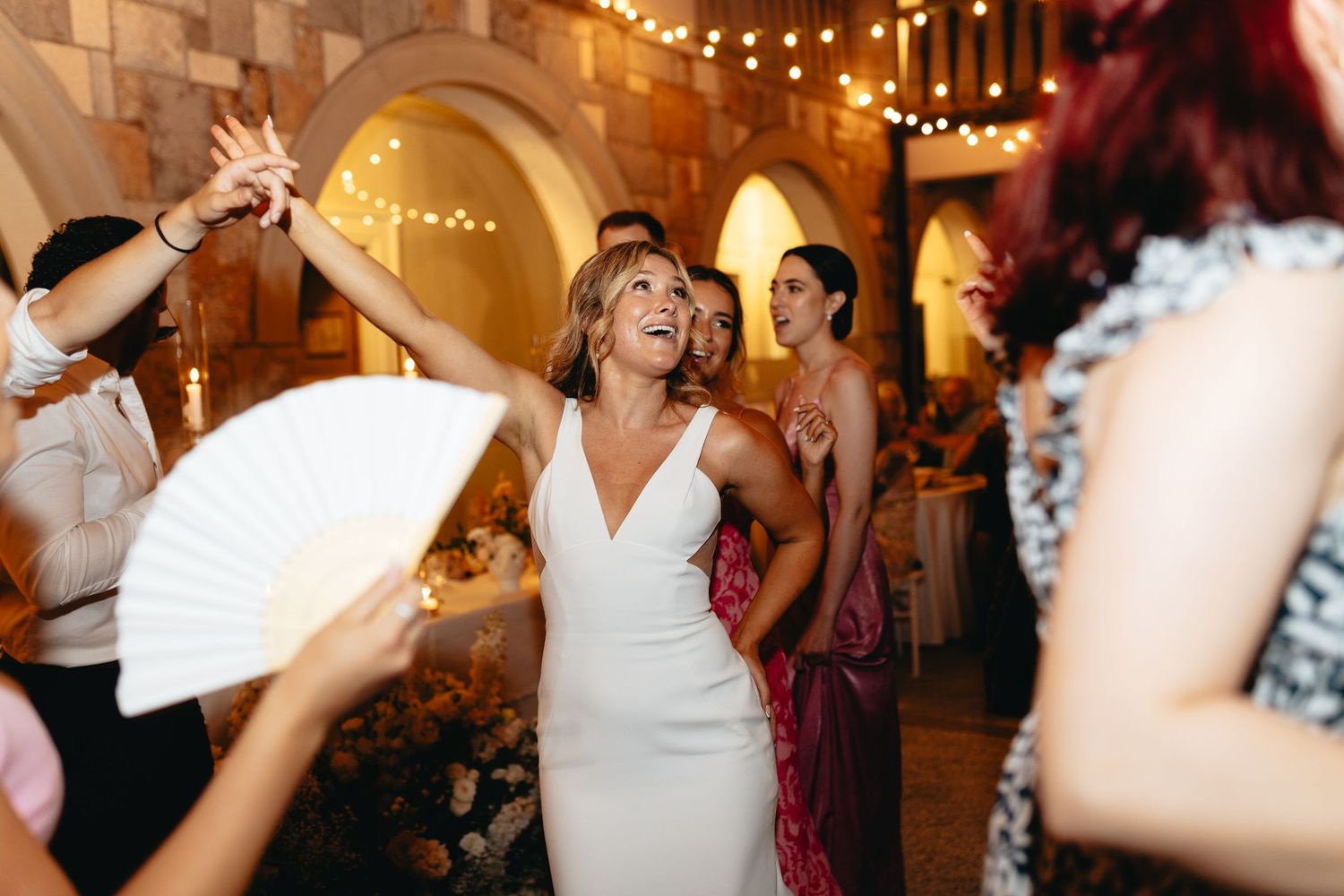 Wedding reception dance party with guests celebrating under warm lighting.