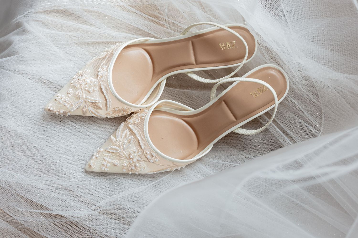 Elegant lace bridal flats in ivory white displayed on delicate tulle fabric.