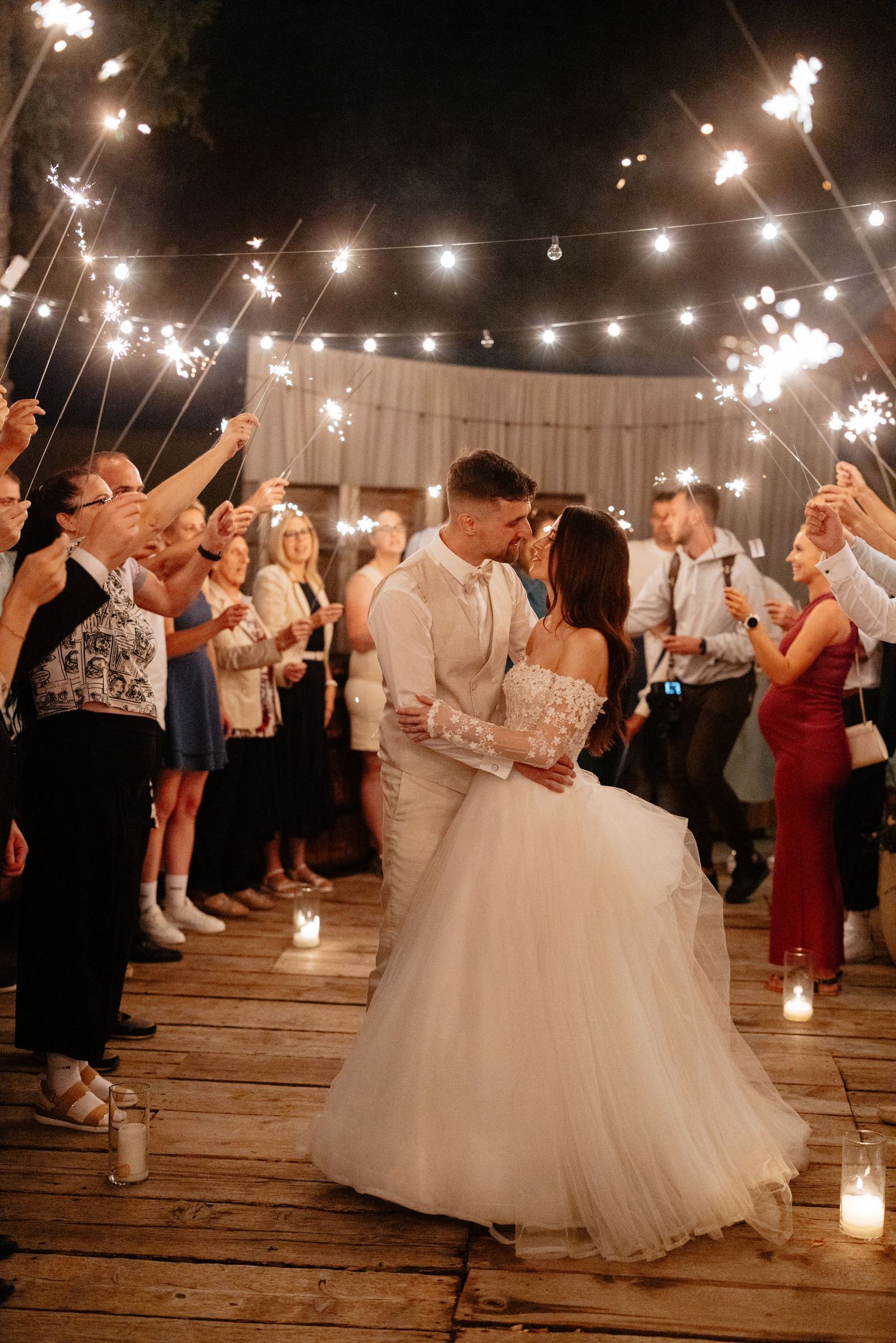 Wedding reception dance floor with string lights overhead as guests dance and celebrate under the warm glow.