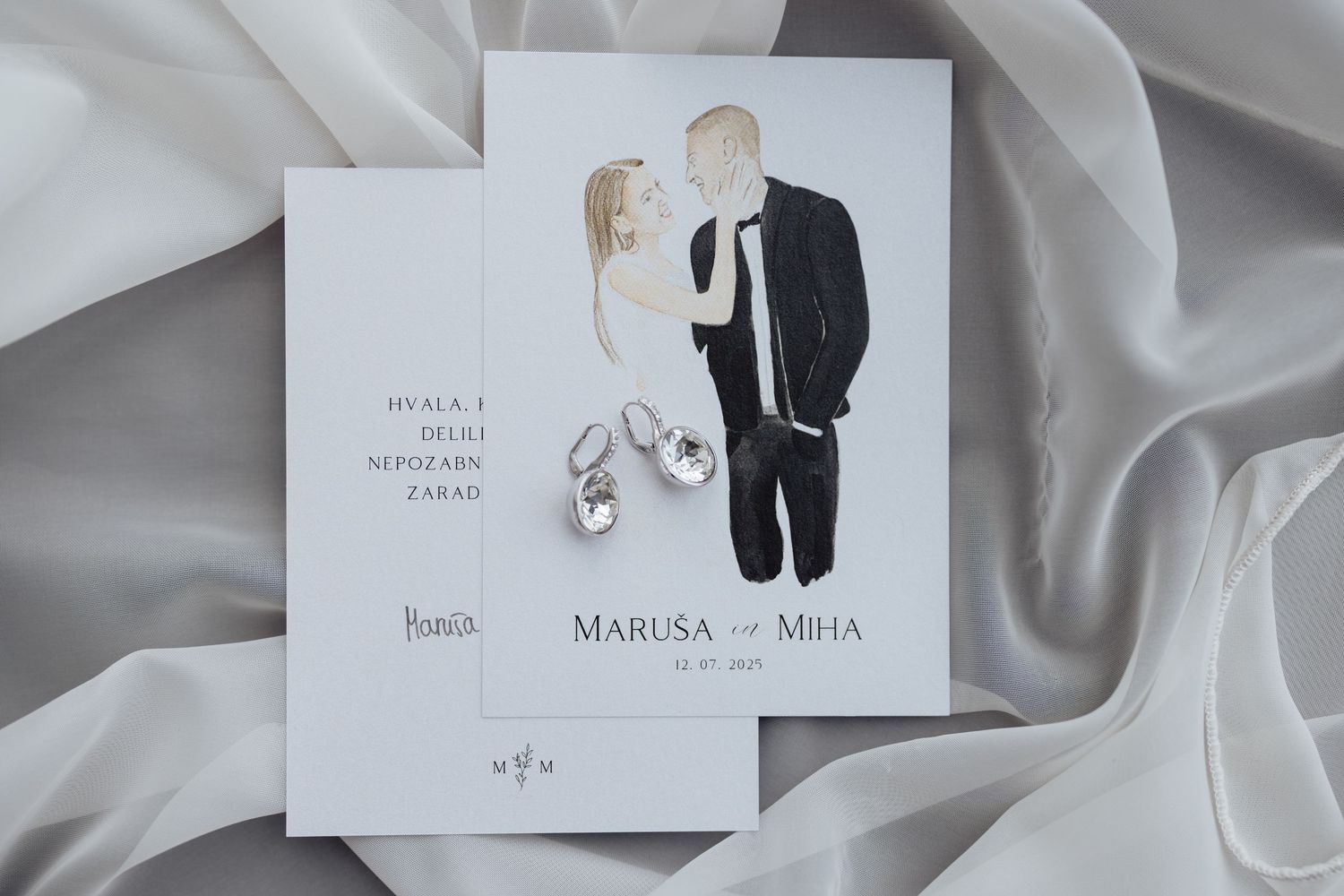 Minimalist wedding invitation designs displayed on light gray fabric.