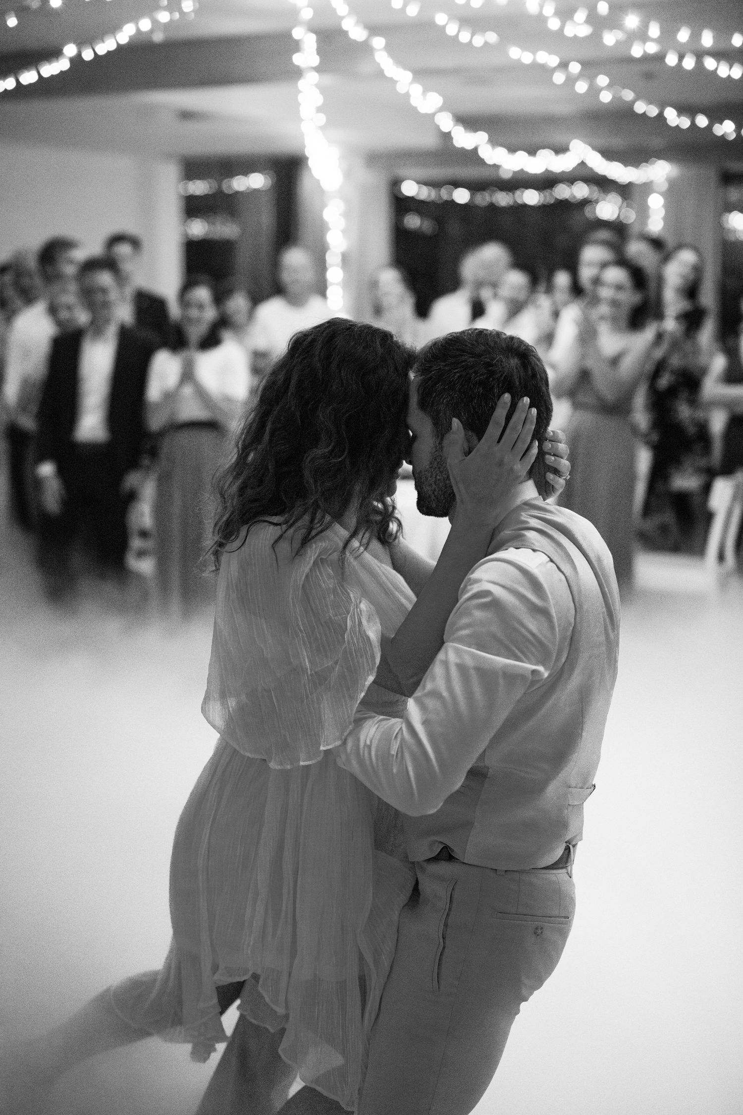 A black and white photo series showing a couple dancing closely together in a romantic moment on a dance floor.