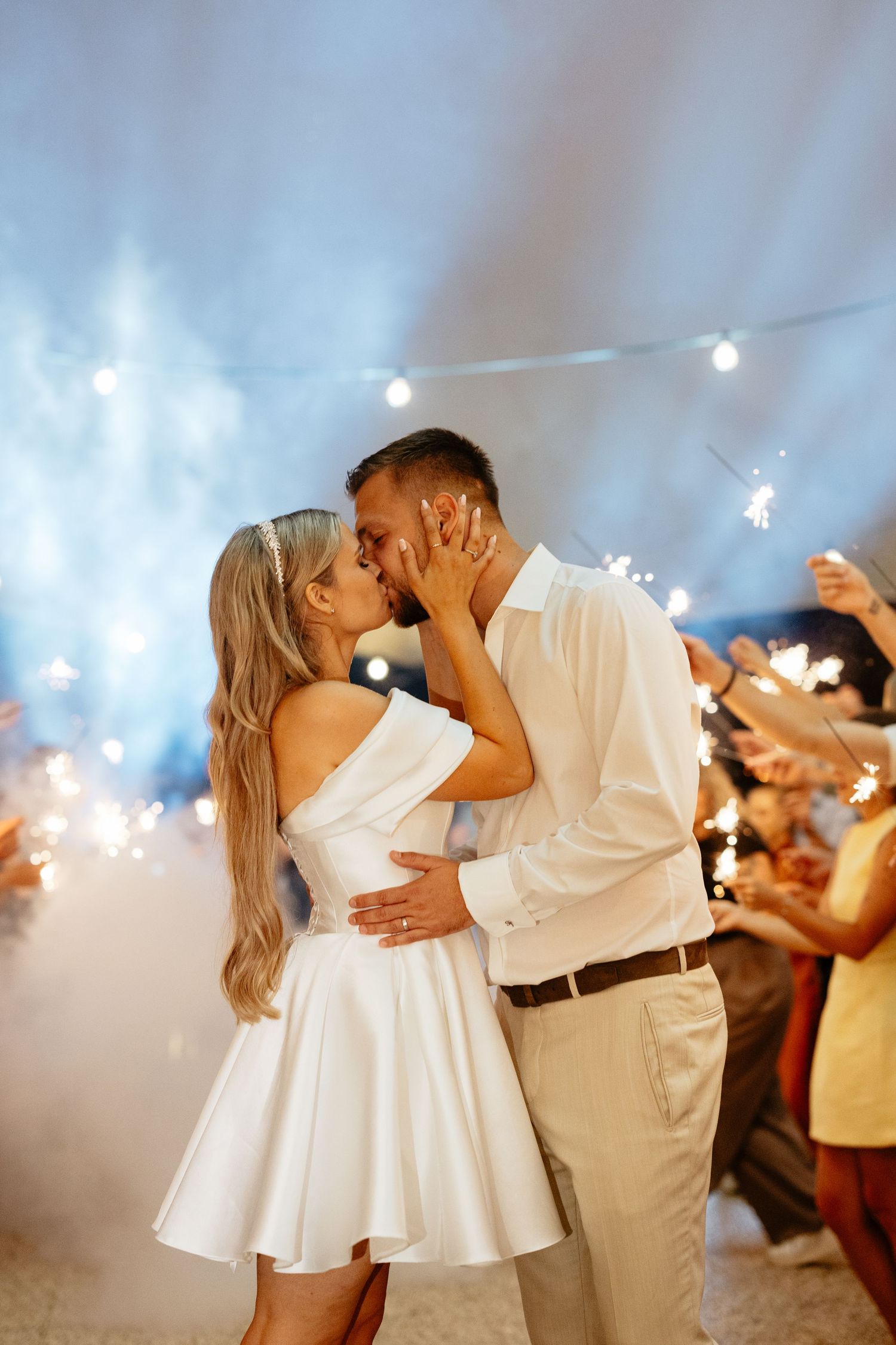 A couple shares a romantic kiss during their sparkler exit celebration.