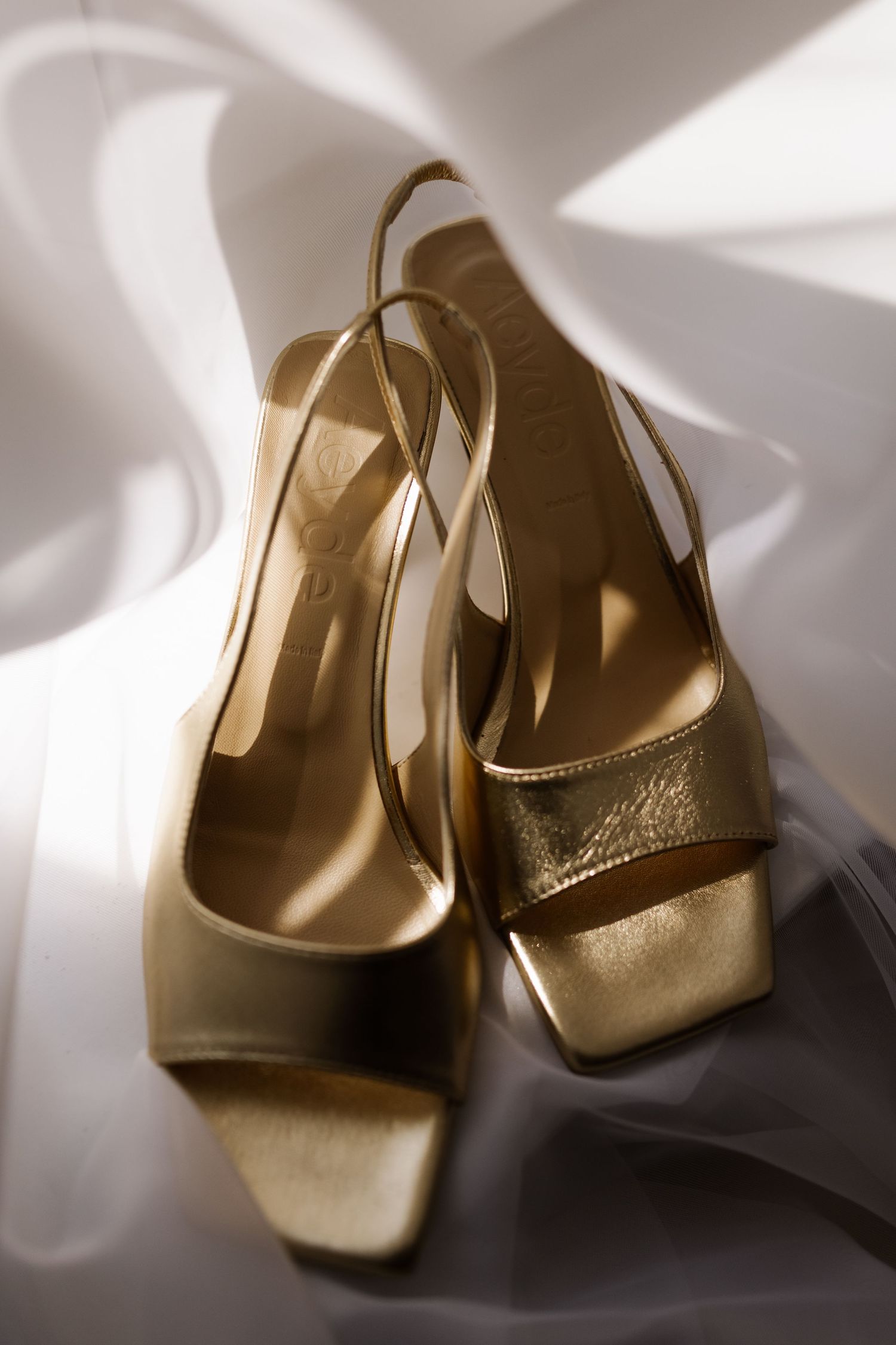 Elegant gold metallic wedding shoes photographed in soft natural light.