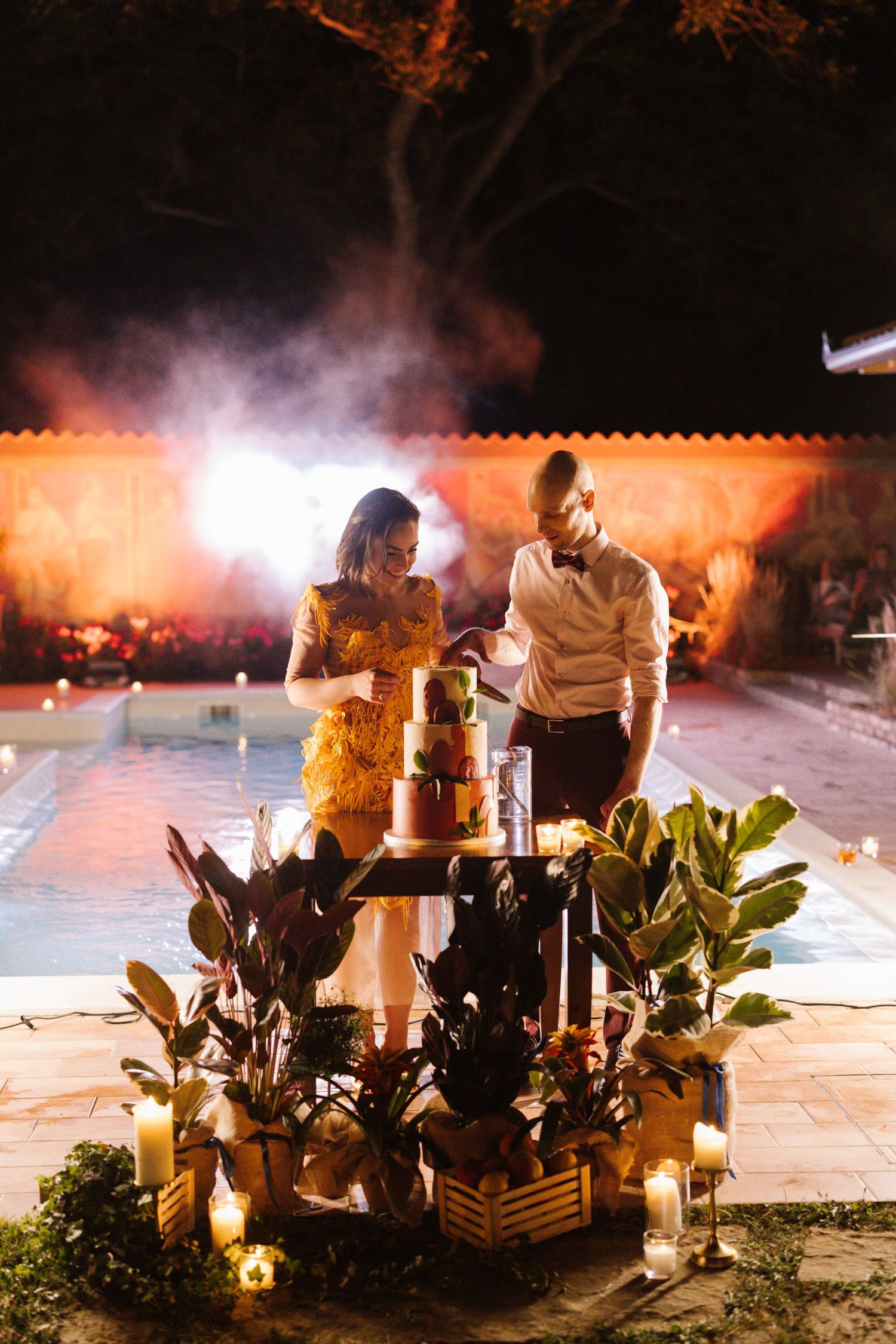 Romantic nighttime outdoor reception with glowing lanterns and lush greenery decorations.