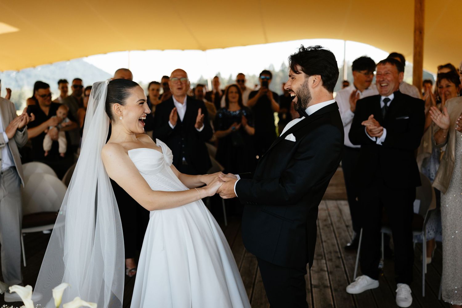 A joyful first dance moment at a wedding reception with guests watching in the background.
