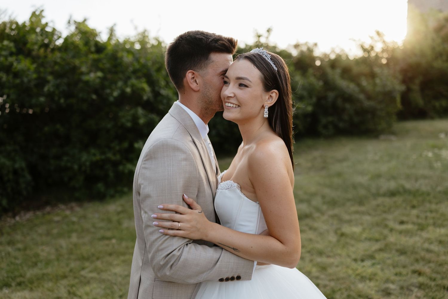 Tender wedding moment captured in outdoor garden setting.