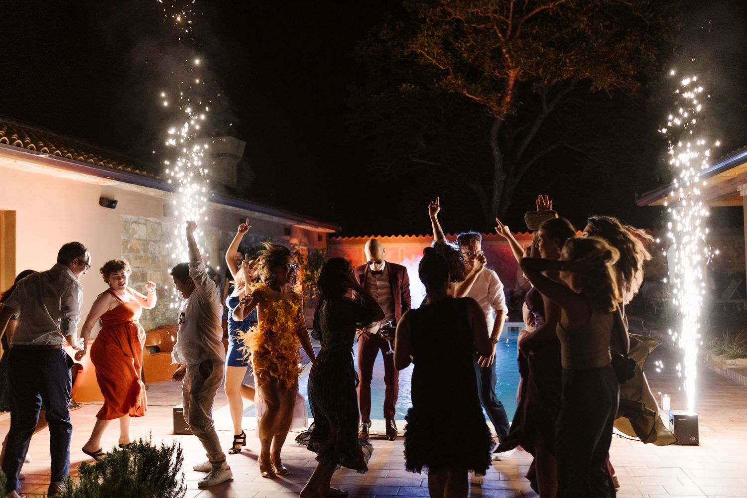 Wedding party dancing at night with sparklers creating a festive atmosphere.