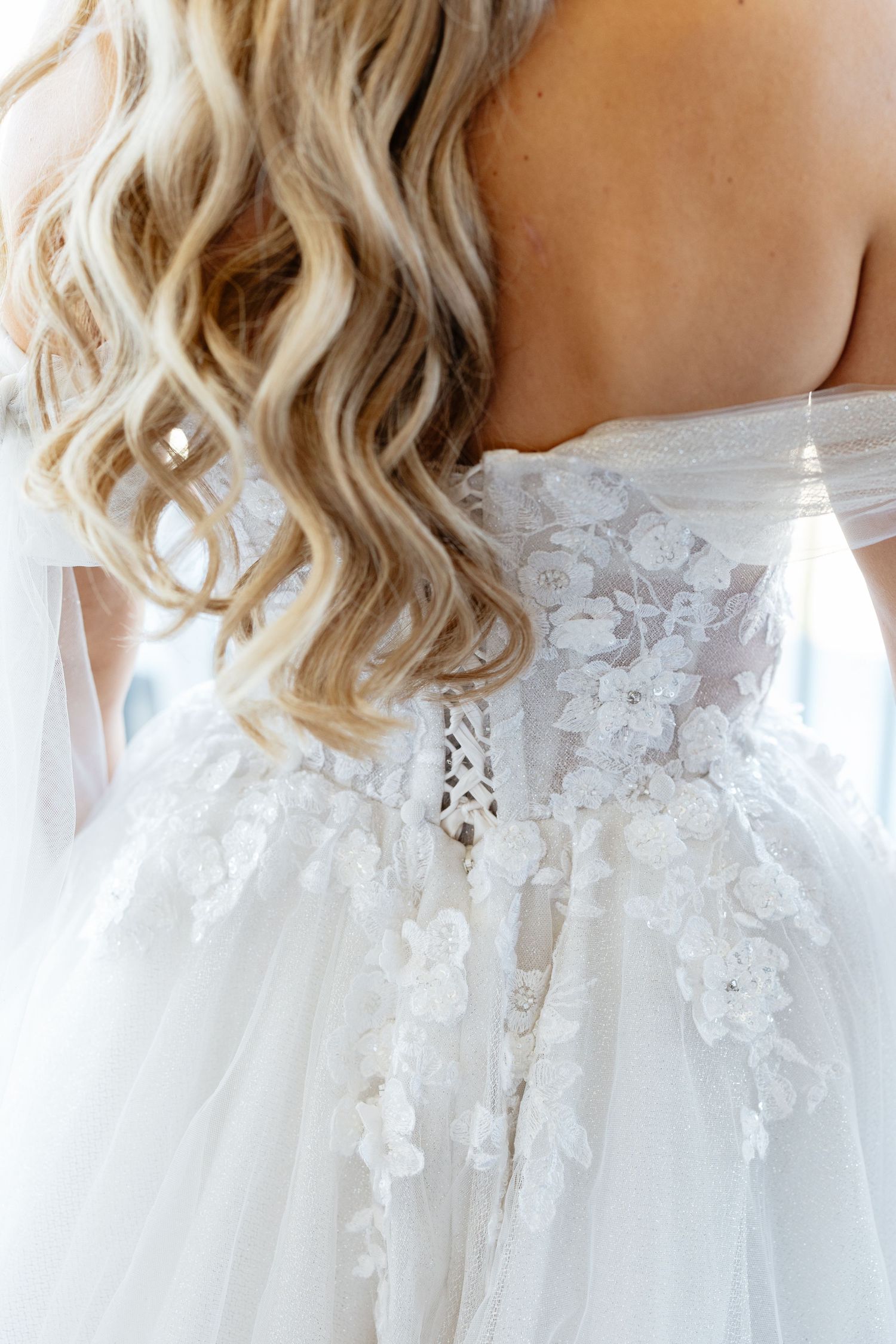 Close-up detail of delicate lace and beadwork on white wedding dress bodice.