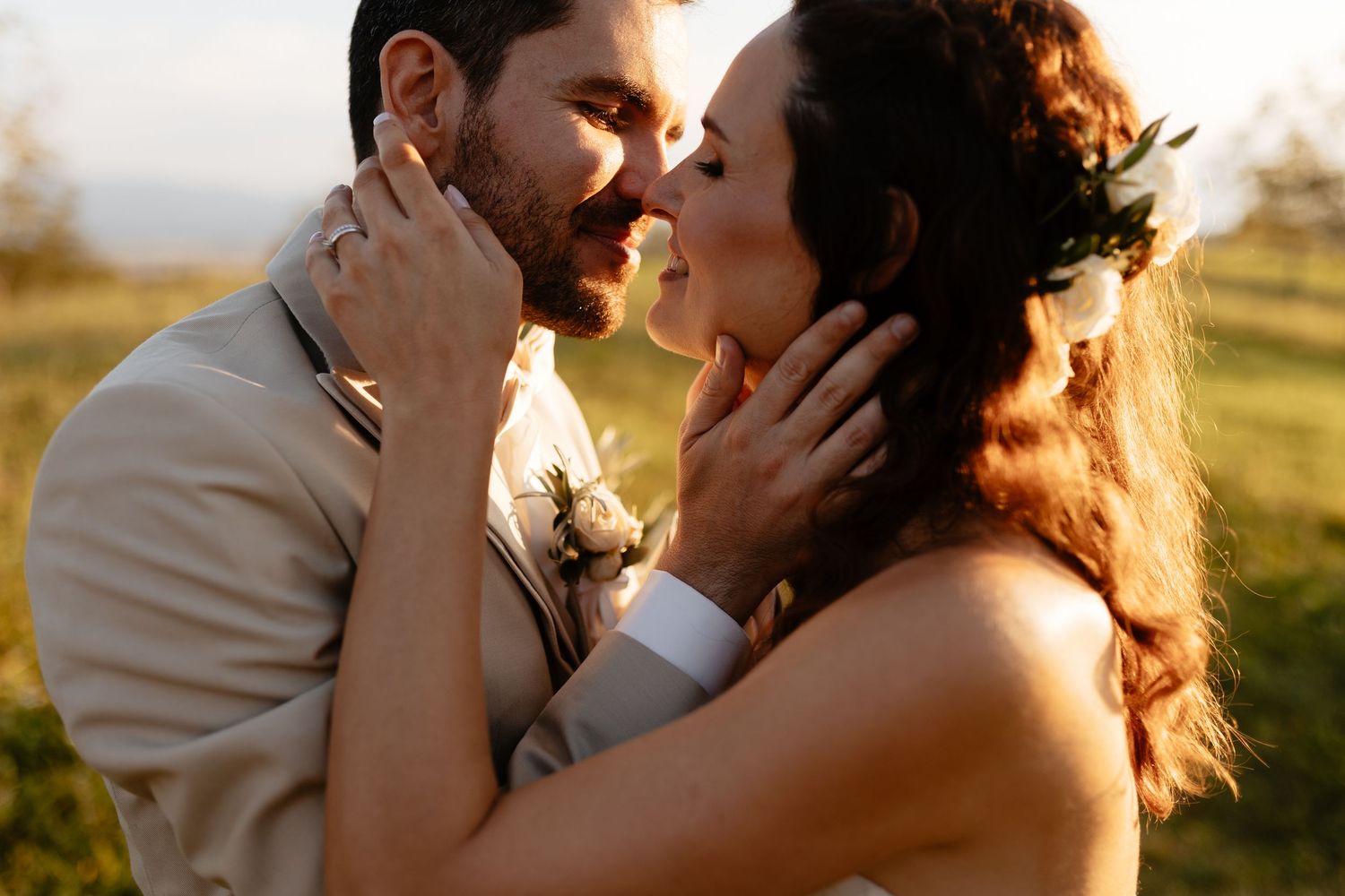 A romantic wedding couple embraces in golden sunlight during their sunset portrait session.