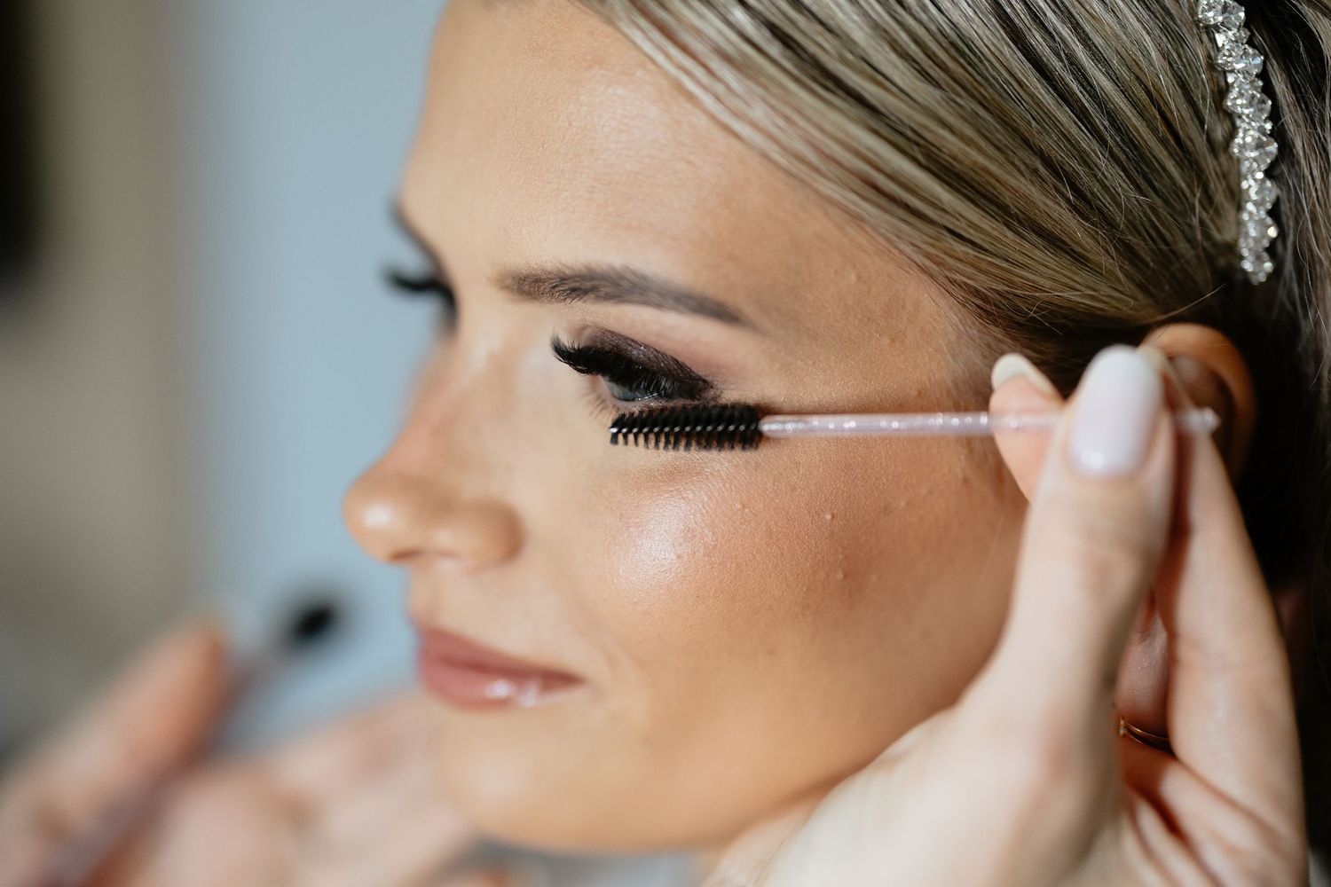Close-up shot of mascara being applied to long eyelashes during bridal makeup preparation.