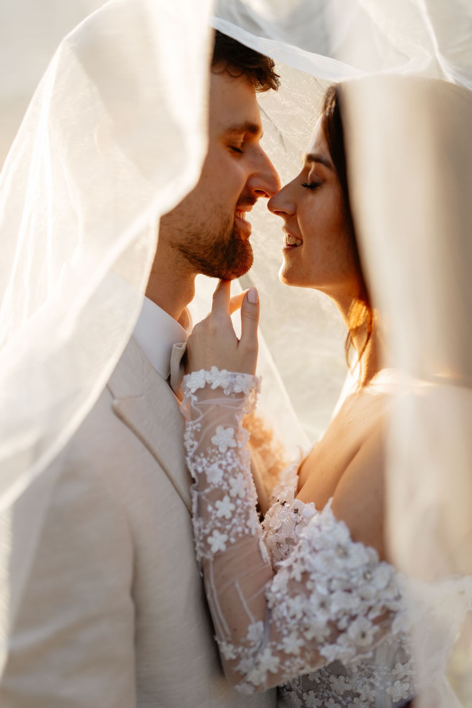 Intimate moment under a sheer veil during a wedding at golden hour.