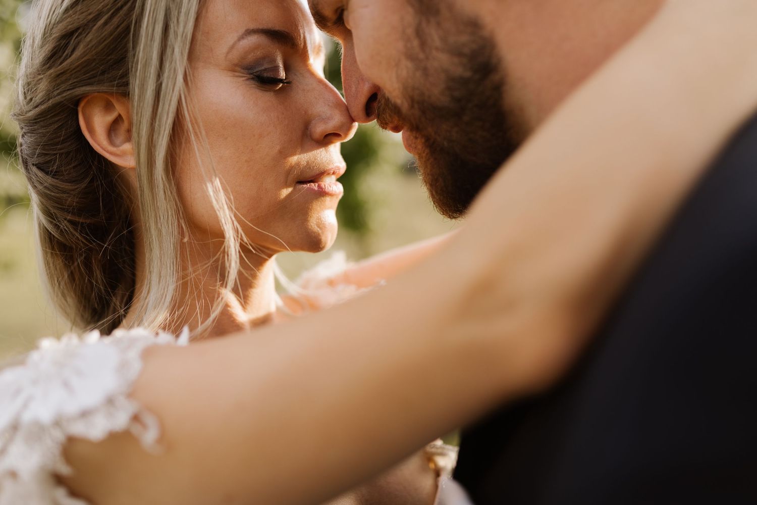 Close up romantic moment between newlyweds in soft natural lighting during their wedding day.