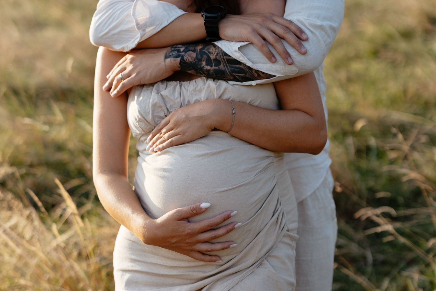 Close-up maternity photos showing loving embrace in natural outdoor setting.
