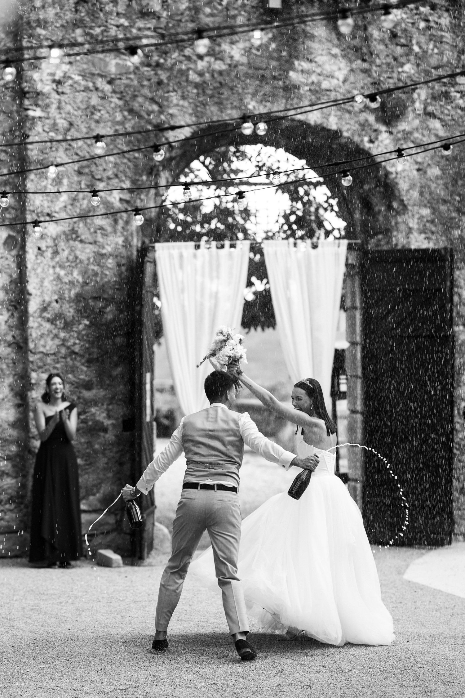 Black and white capture of joyful wedding celebration with confetti and dancing.