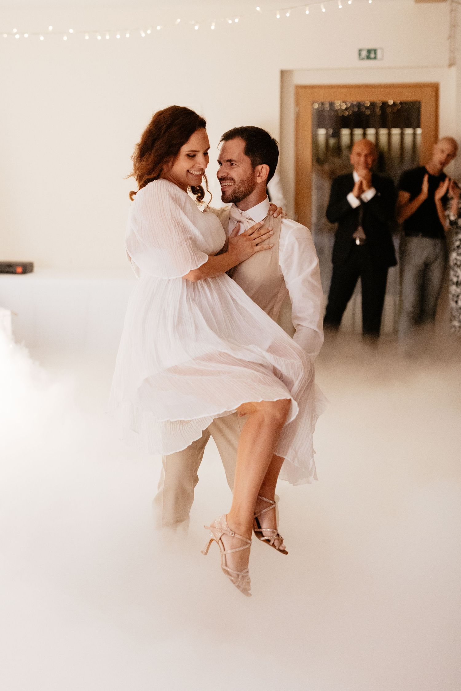 Romantic first dance with fog effect on dance floor as couple spins and embraces.