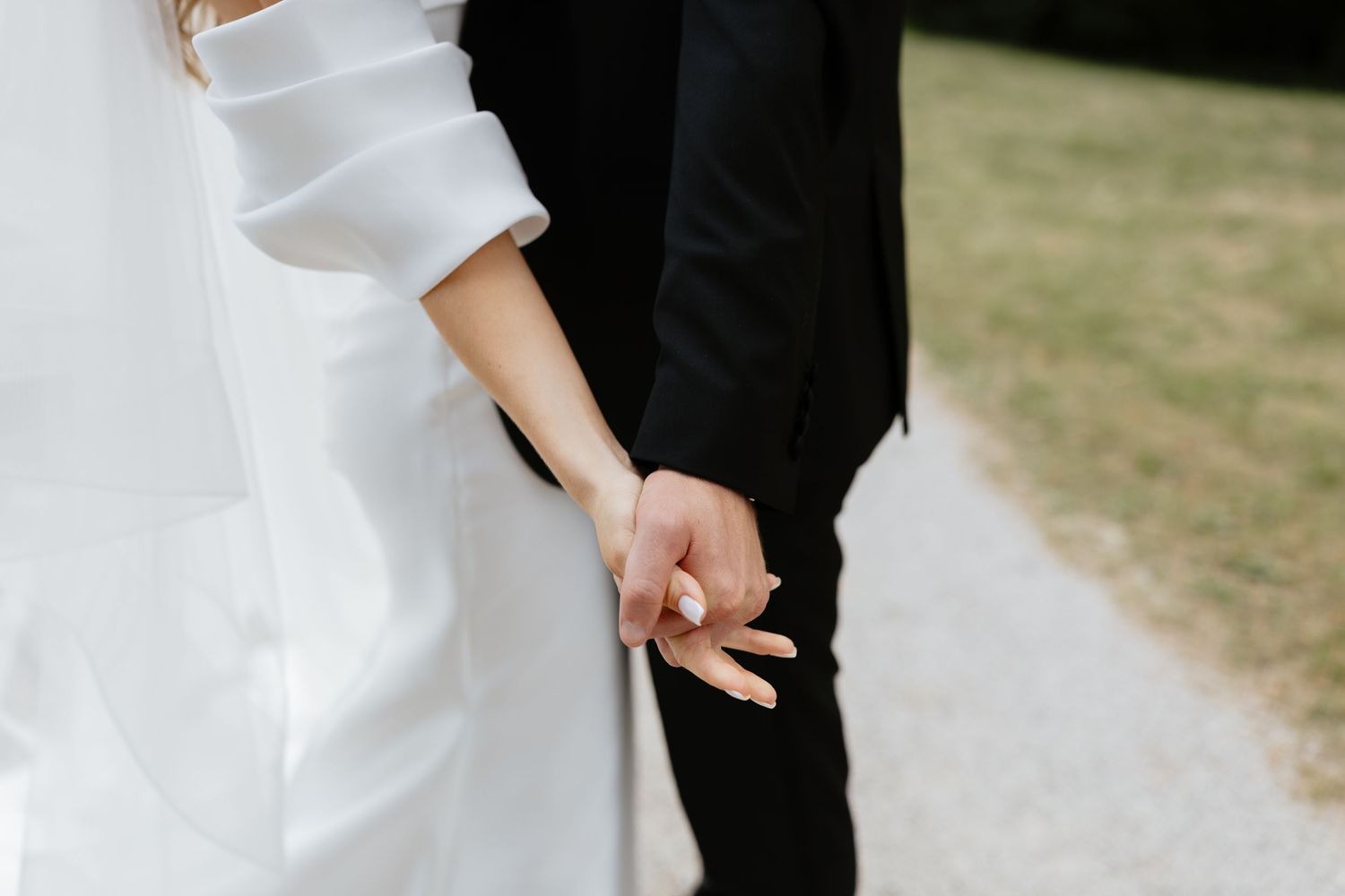 Close-up details of wedding attire showing elegant white dress and black tuxedo.