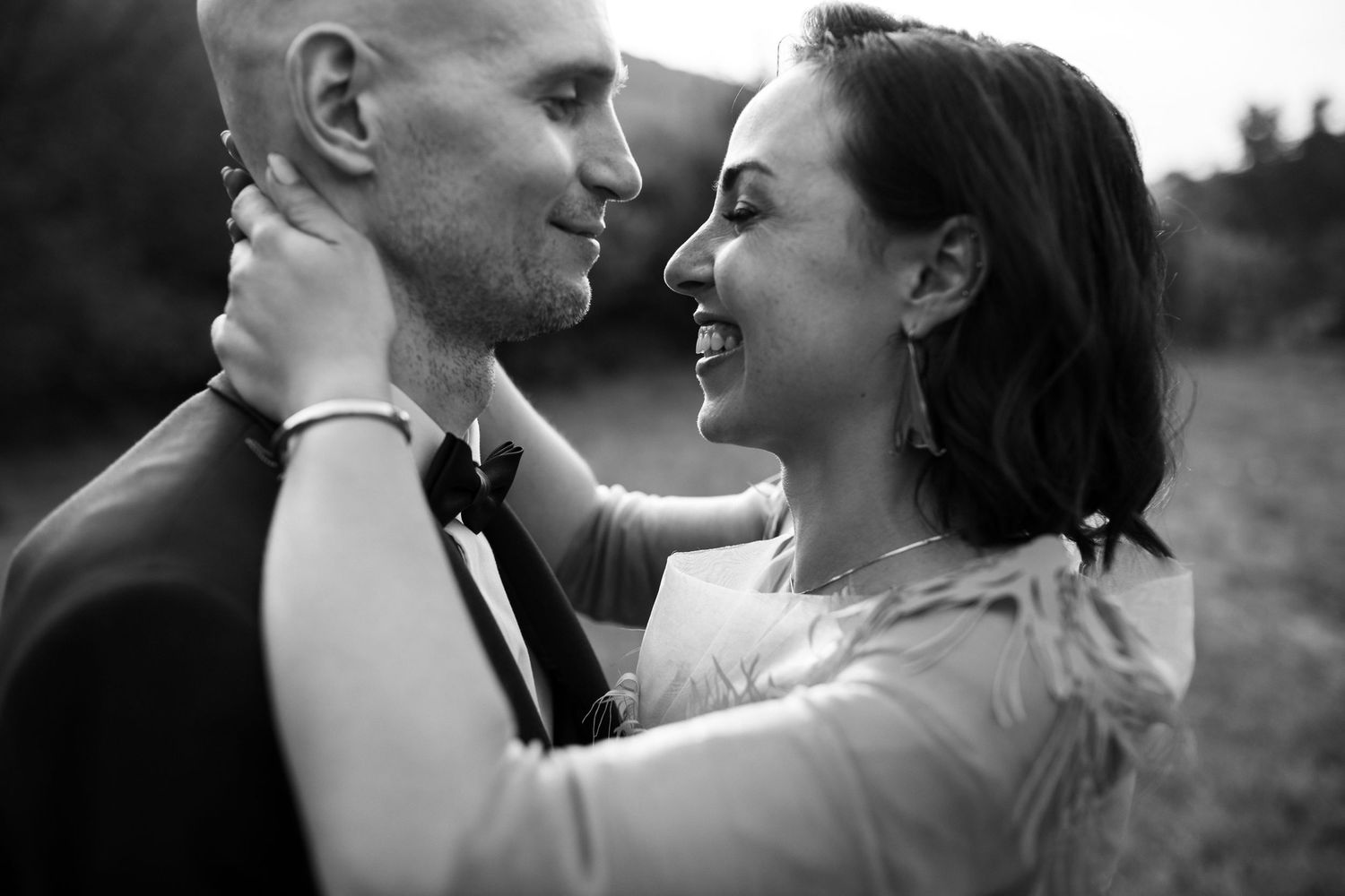A romantic black and white portrait of a couple embracing outdoors.