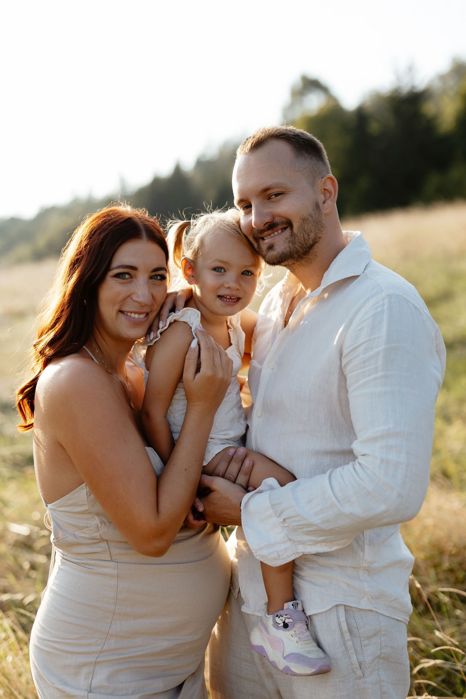 Intimate family portraits captured in golden sunlight against a natural outdoor backdrop.