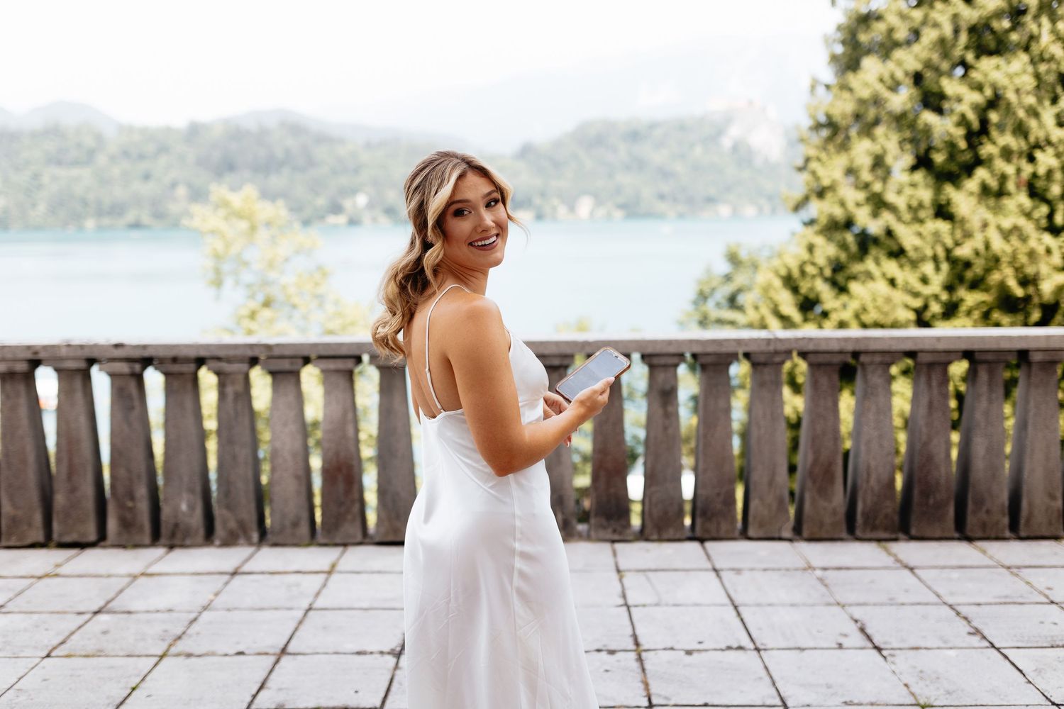 Wedding party posing on a wooden deck overlooking a beautiful mountain lake landscape.