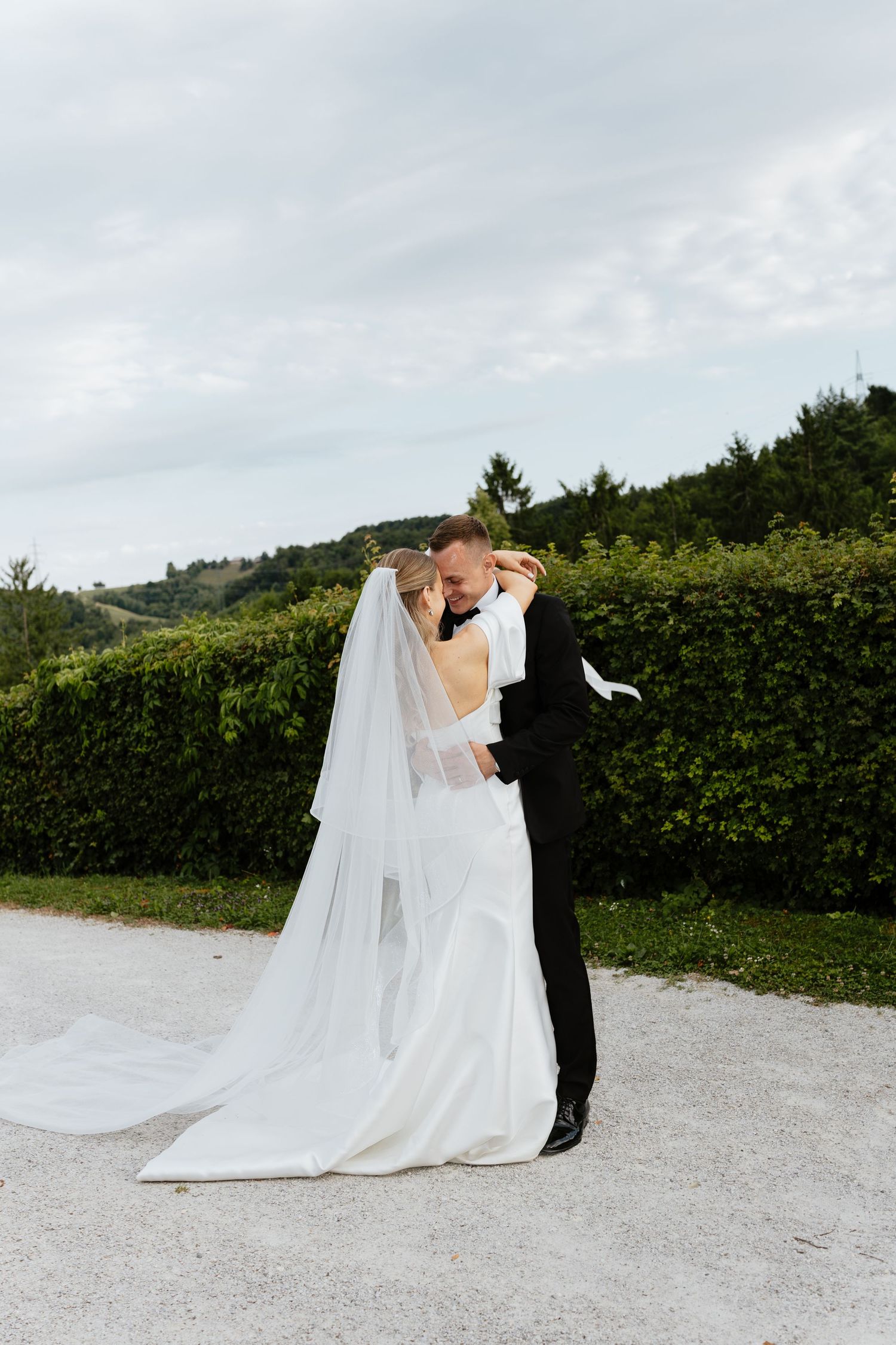 Elegant wedding couple sharing romantic moments on a scenic mountain path.