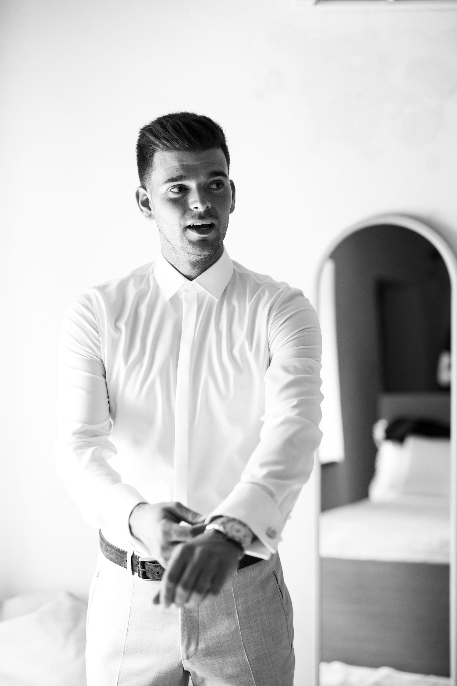 Black and white photos of a groom getting ready in a white dress shirt.