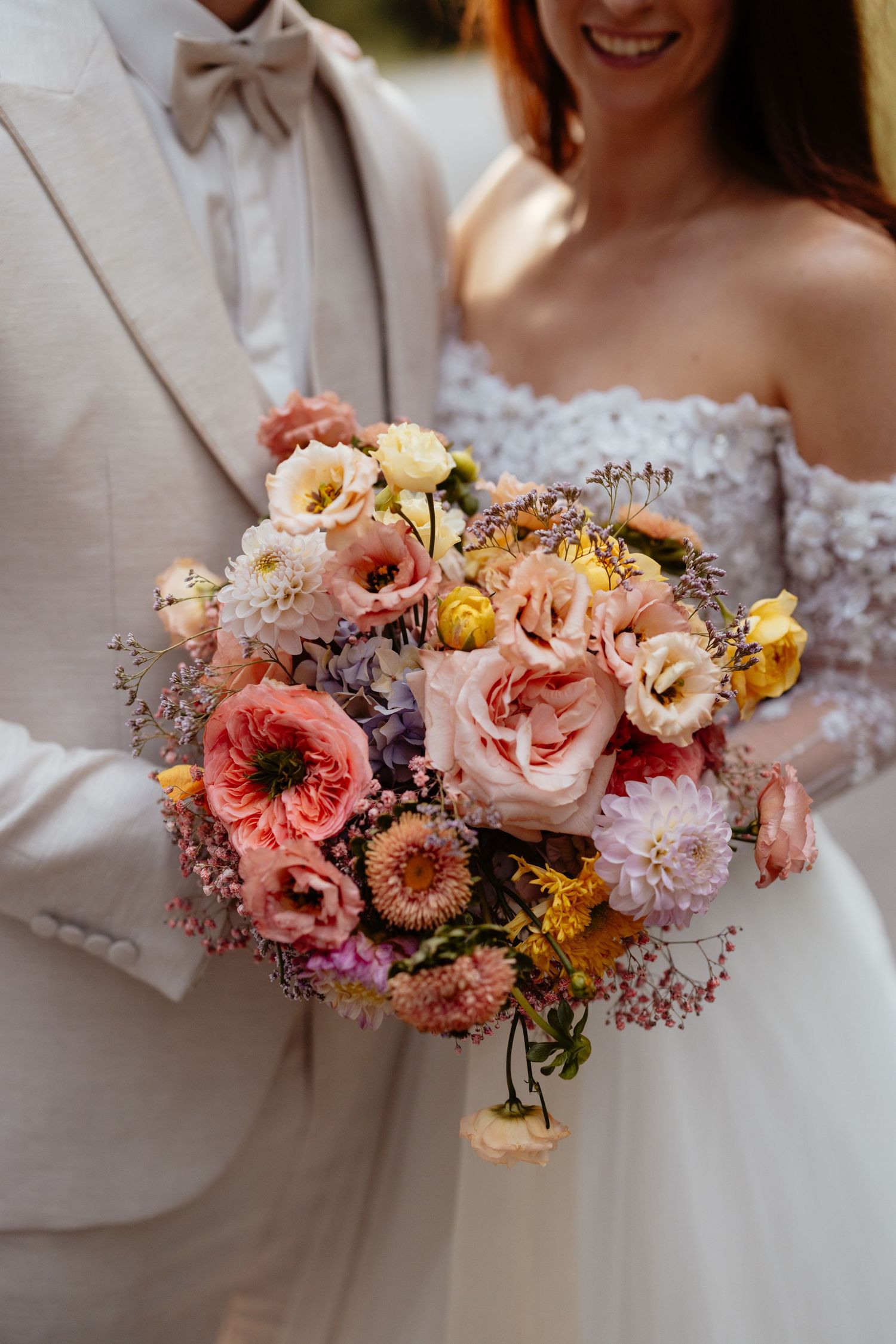 A stunning wedding bouquet featuring coral and peach roses with yellow accents in a romantic arrangement.