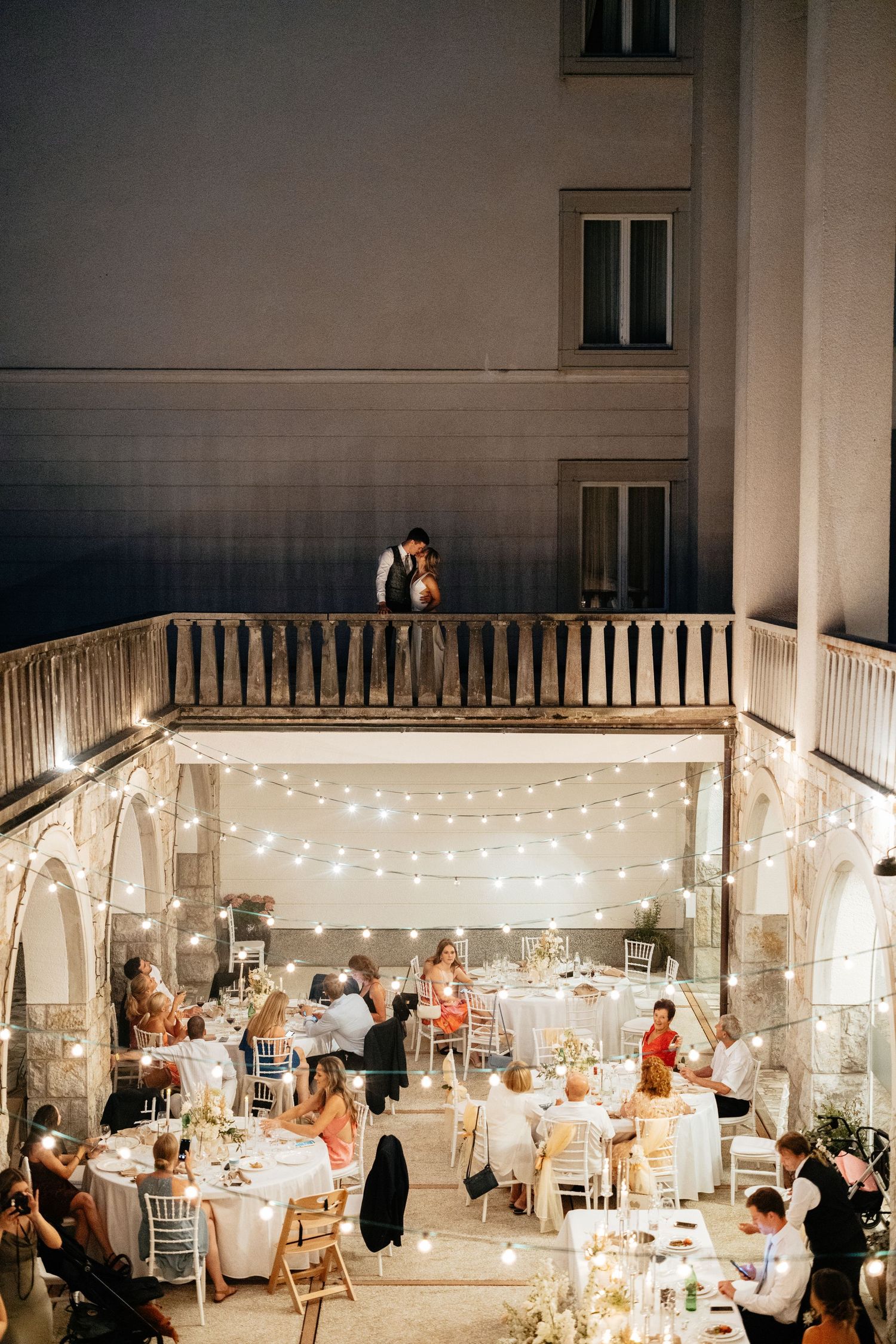 Wedding reception venue decorated with string lights and white tables for an evening celebration.