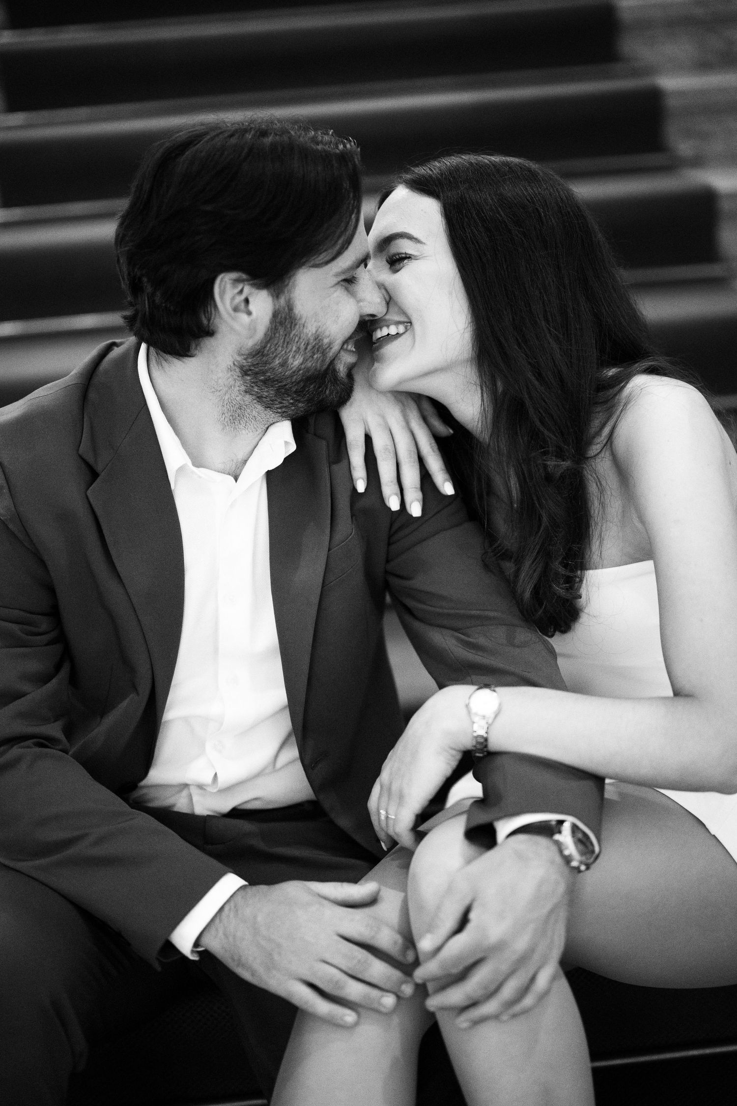 An intimate black and white photo of a couple sharing a tender moment on steps.