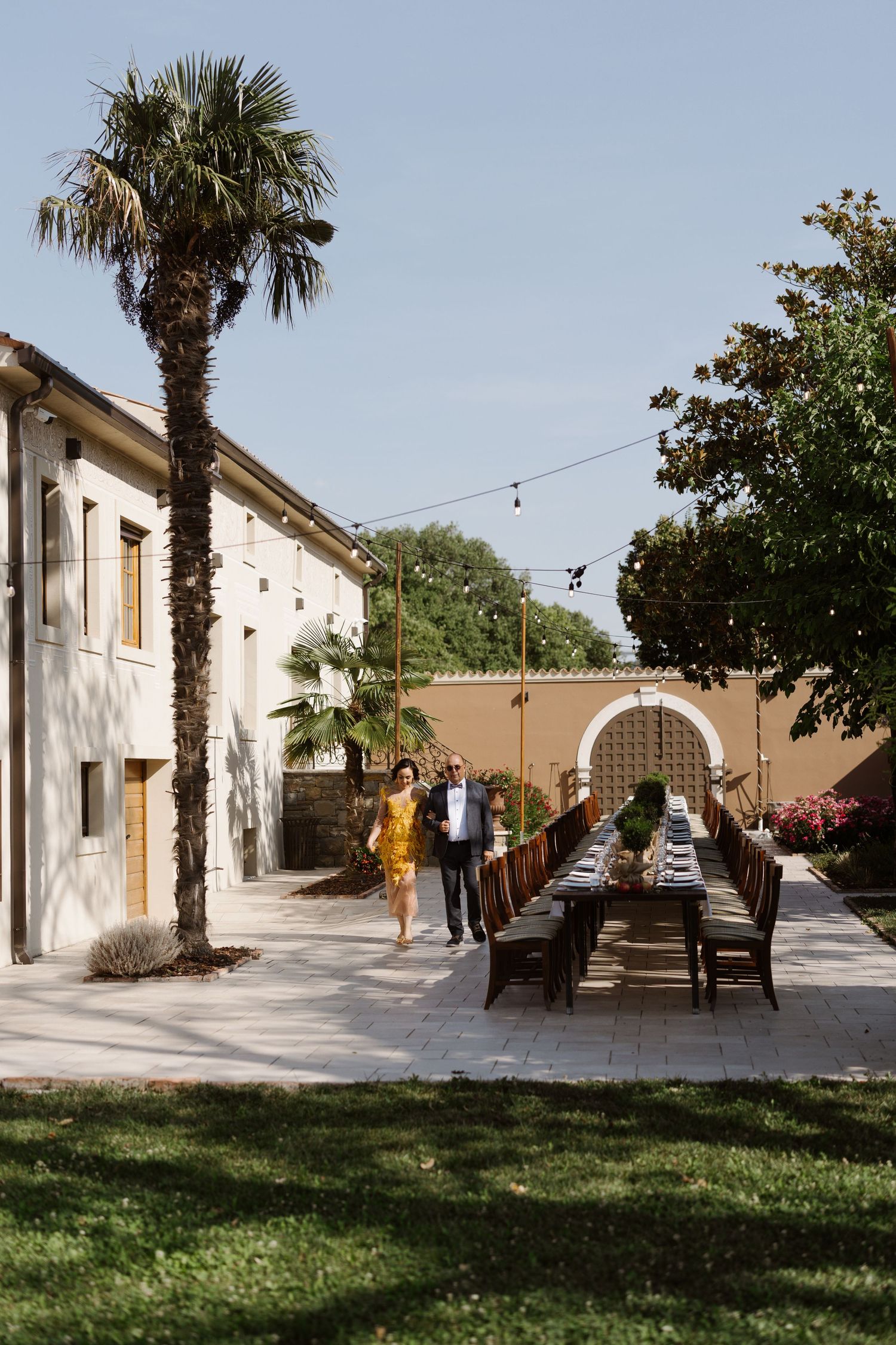 A sunny outdoor courtyard with palm trees and white stucco buildings in Spanish colonial style.