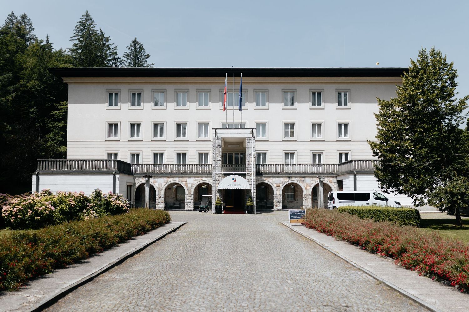 A series of white modern buildings with arched entrances and landscaping shown from different angles and perspectives.