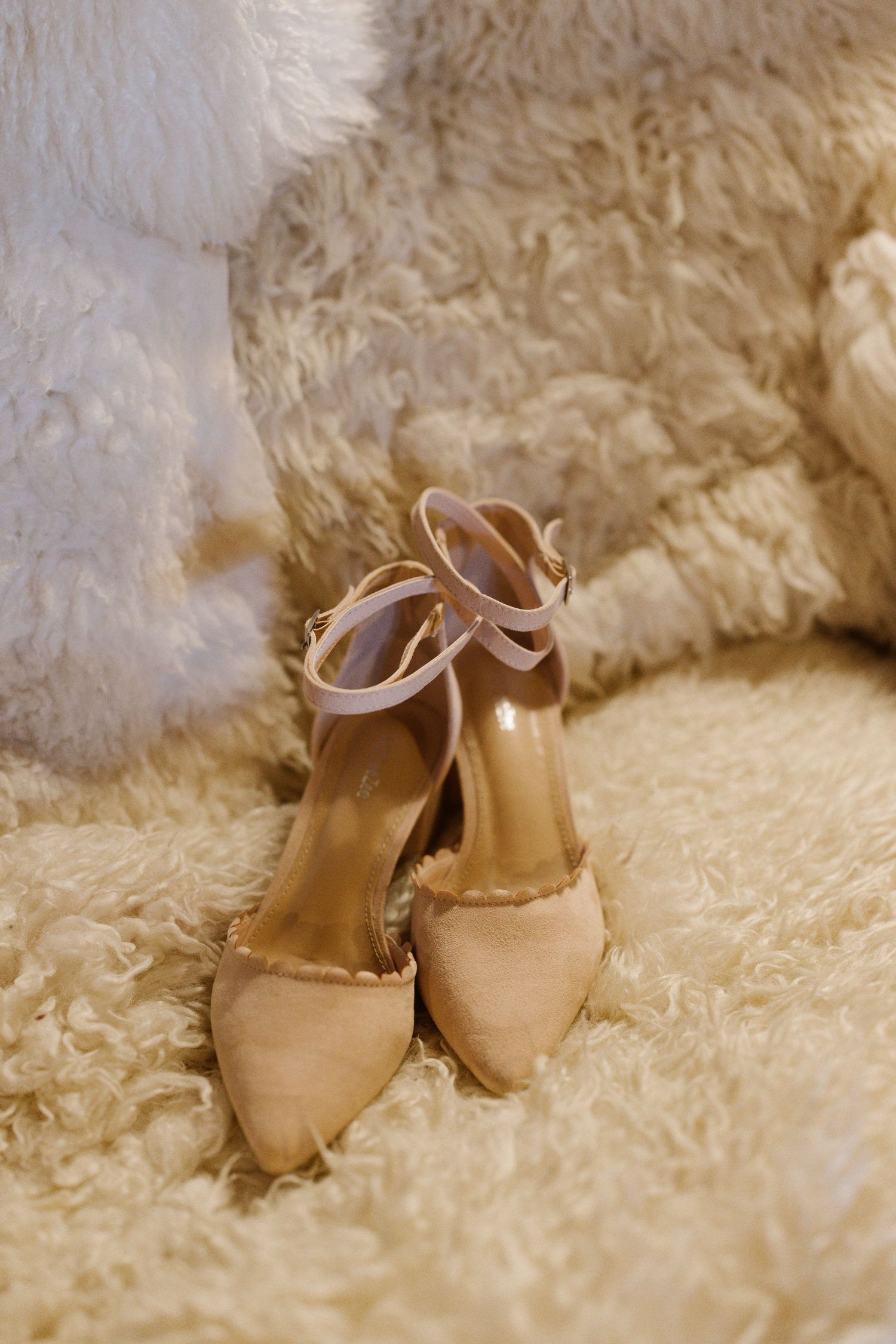 Beige wedding shoes resting on soft white fur or carpet in a series of romantic detail shots.