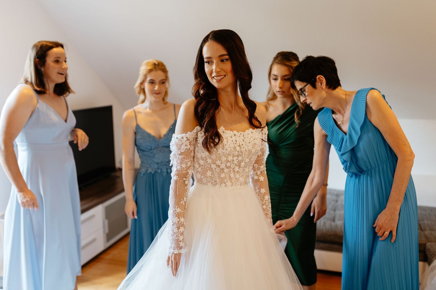Bridesmaids in turquoise blue dresses help the bride prepare for her wedding day.