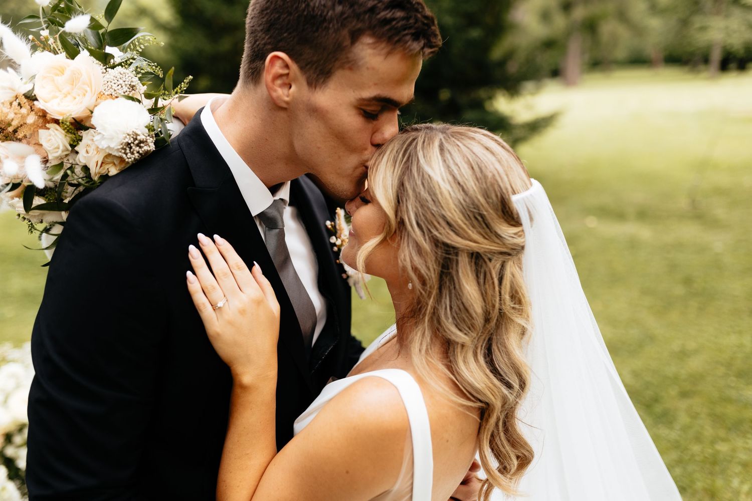 Romantic wedding couple embracing outdoors in formal attire.