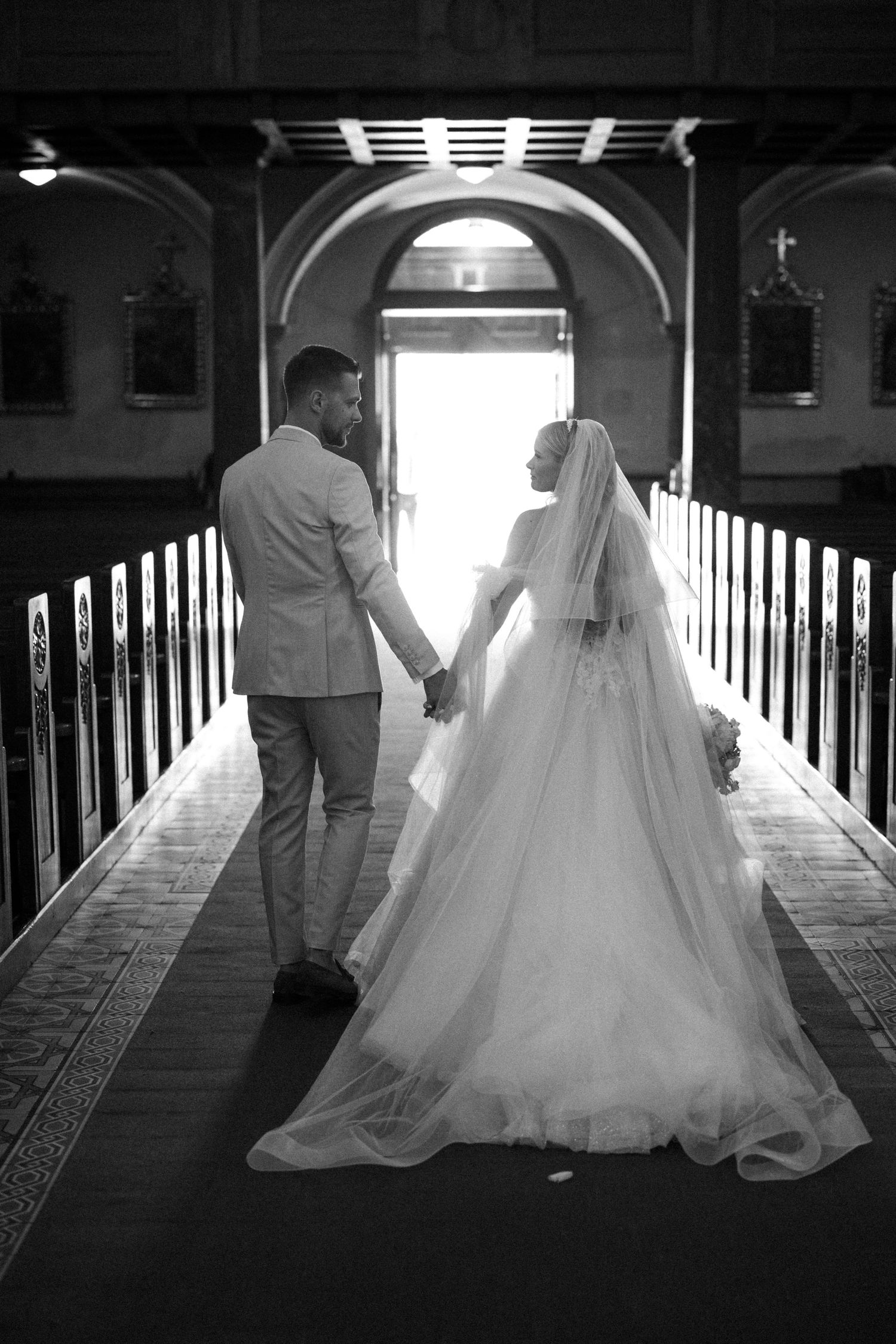 Black and white sequence of silhouettes walking down a church aisle in dramatic lighting.