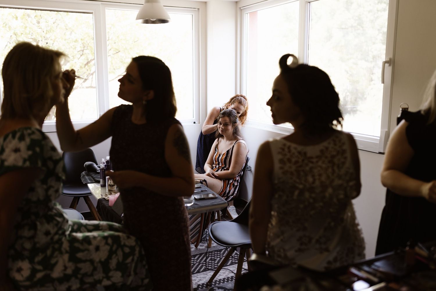 People gather in a bright room with large windows for what appears to be a social or educational event.
