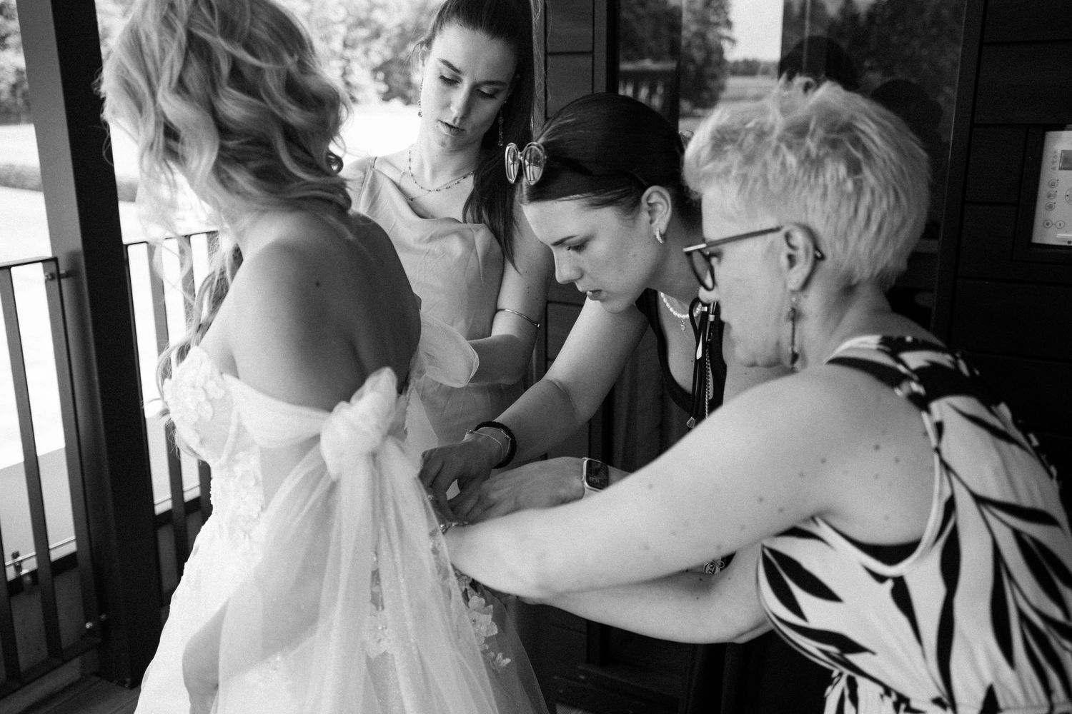 Black and white photo of wedding party getting ready in intimate indoor setting.