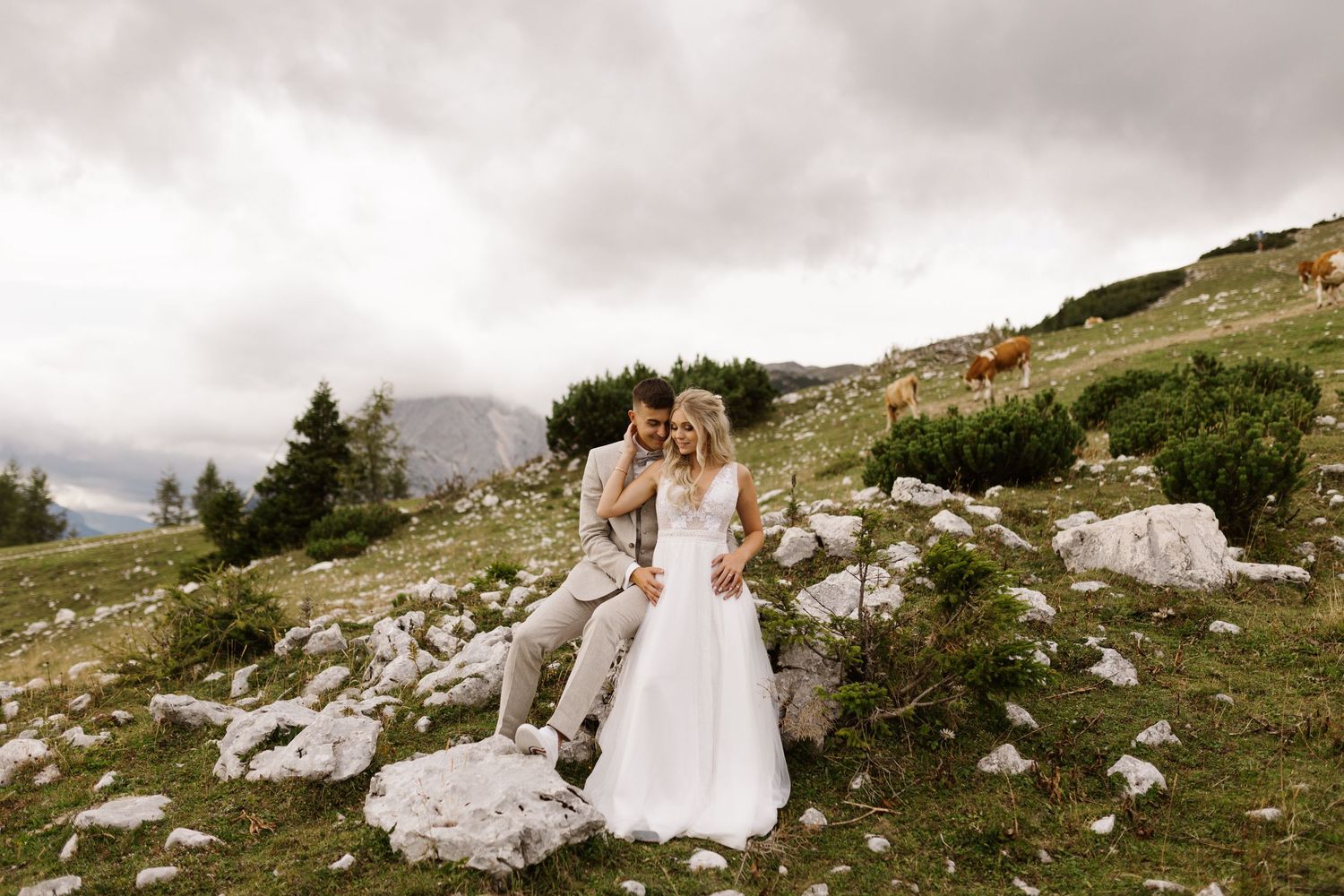 Scenic mountain wedding photos with couple posing among rocky terrain and evergreen trees.