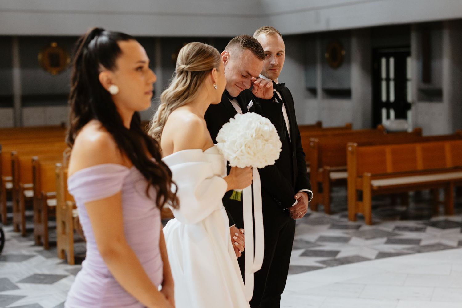 Wedding ceremony in a church with bridal party and white bouquet.