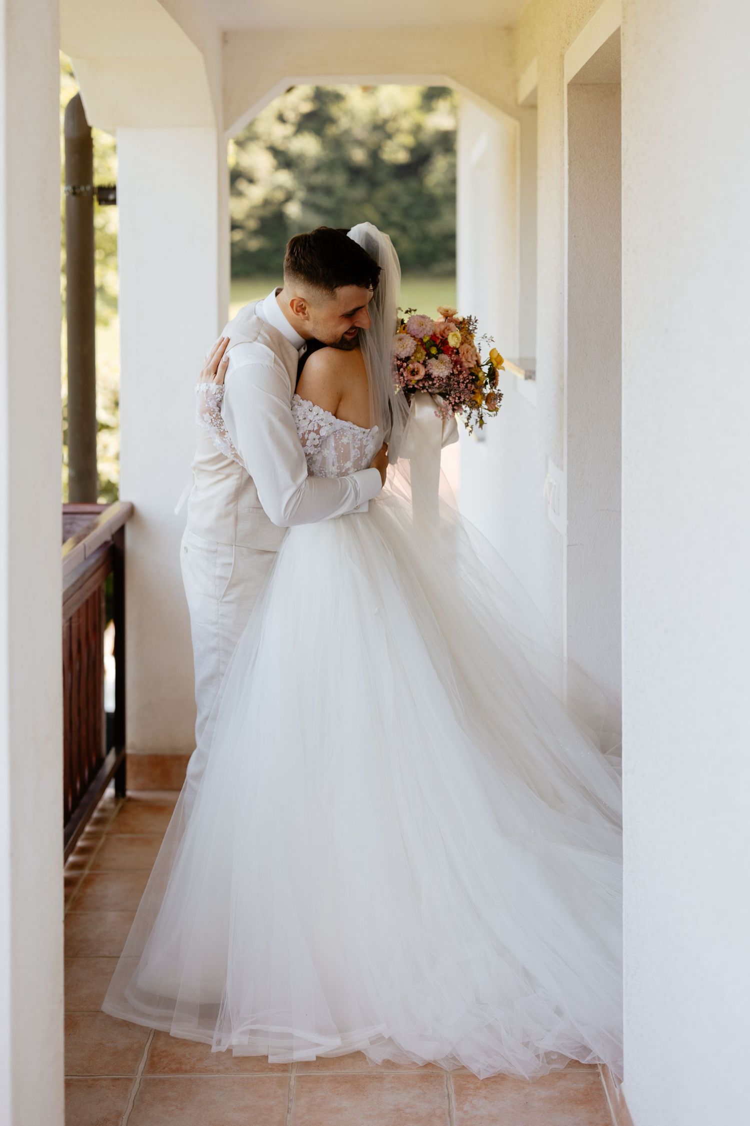 Flowing white wedding dress captured in an elegant covered walkway with columns.
